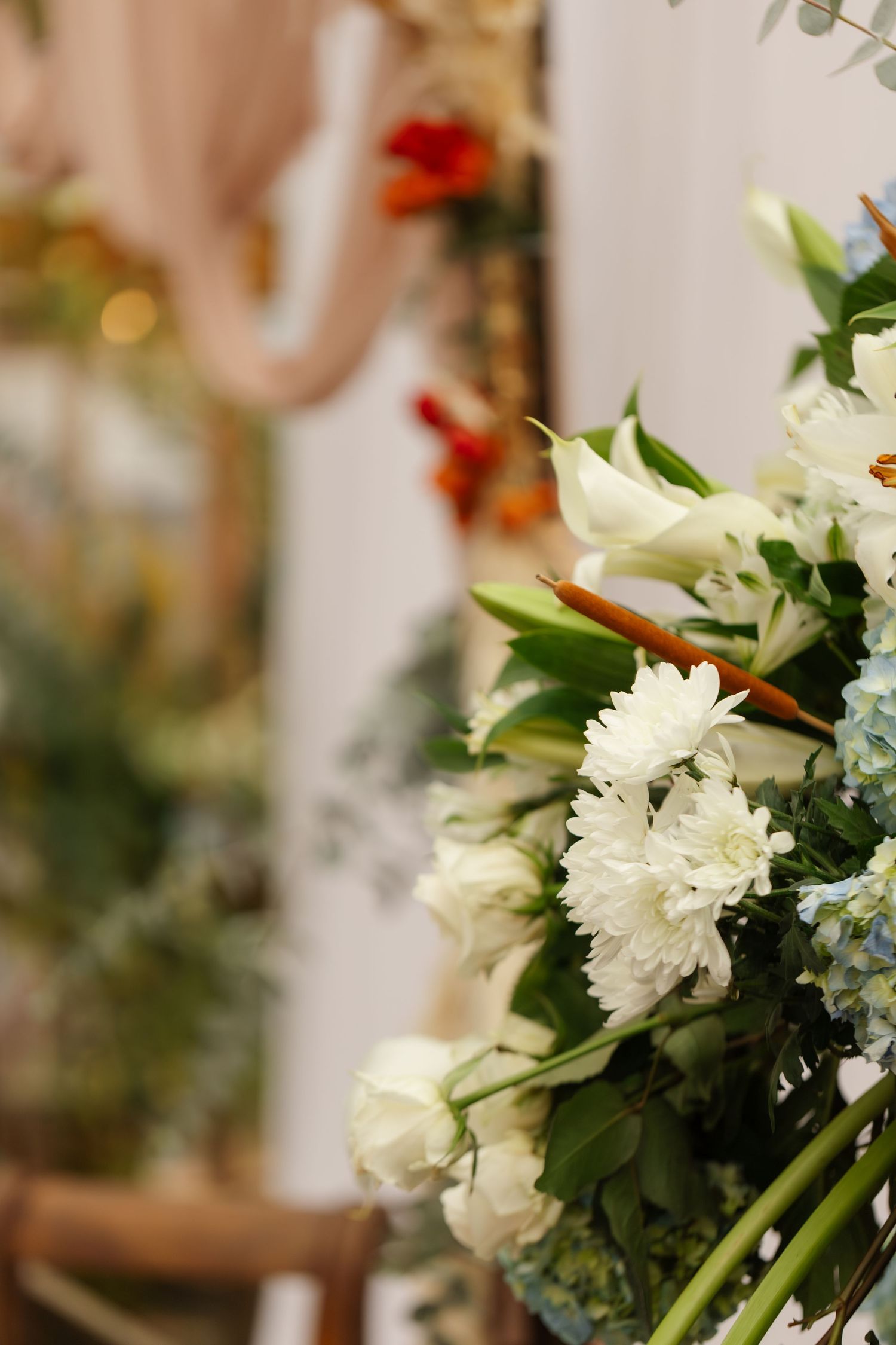 Close-up of elegant white floral arrangement with roses, chrysanthemums, and lilies at a wedding ceremony.