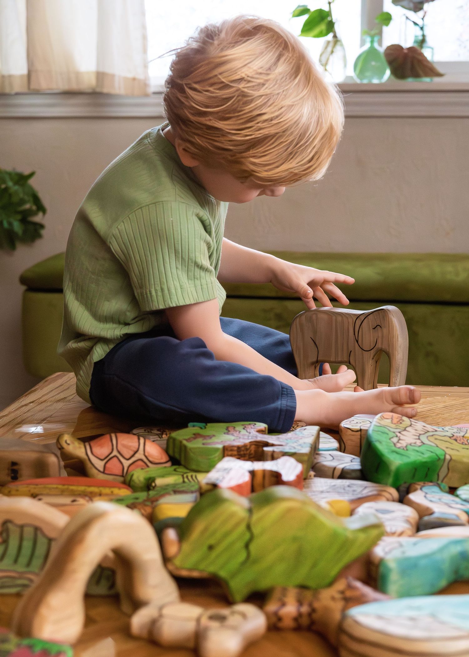 Wooden toy blocks and playthings scattered on green cushioned bench.