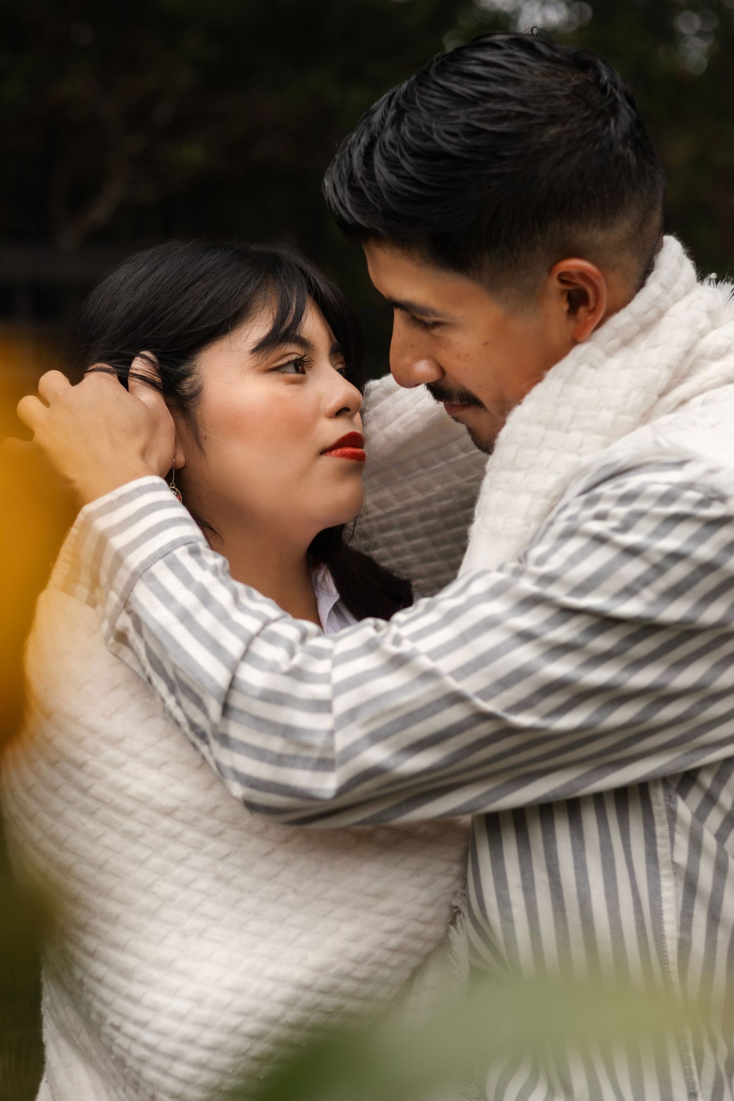 Intimate couple in white and striped clothing embracing in a romantic portrait sequence.