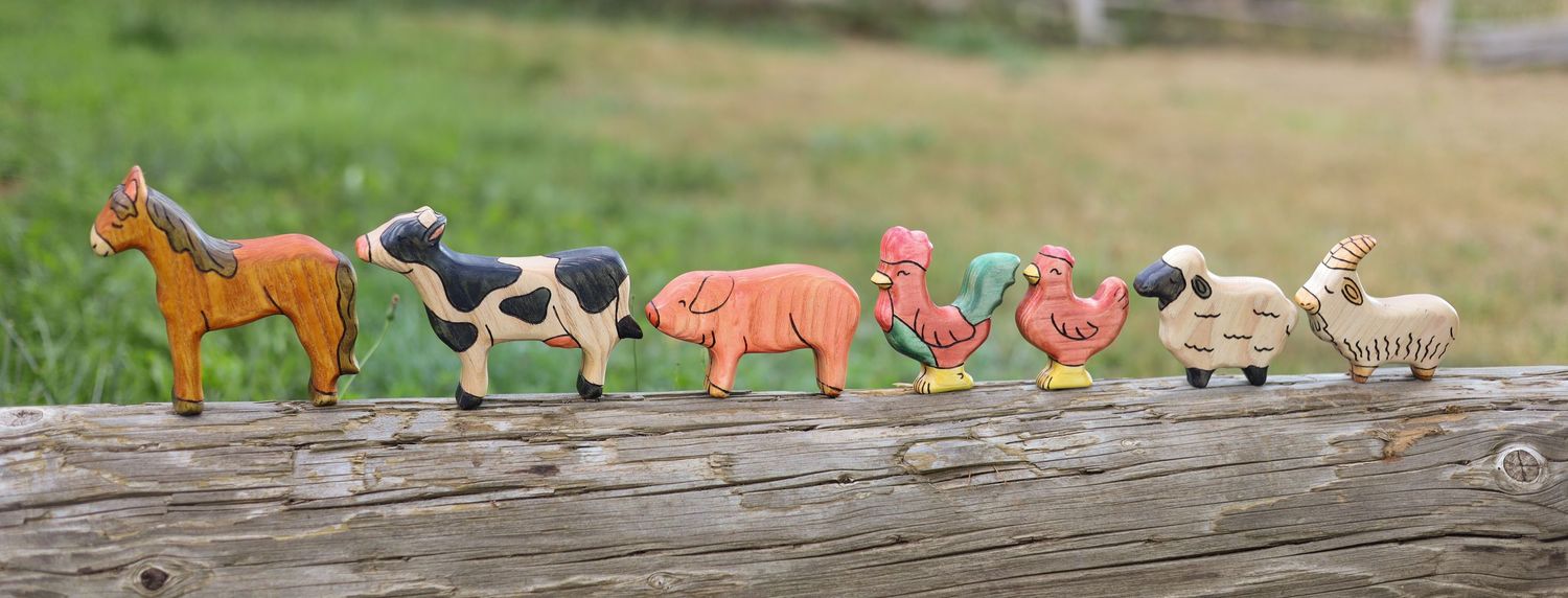 Farm animal and nature themed sugar cookies displayed in a row on a rustic surface.