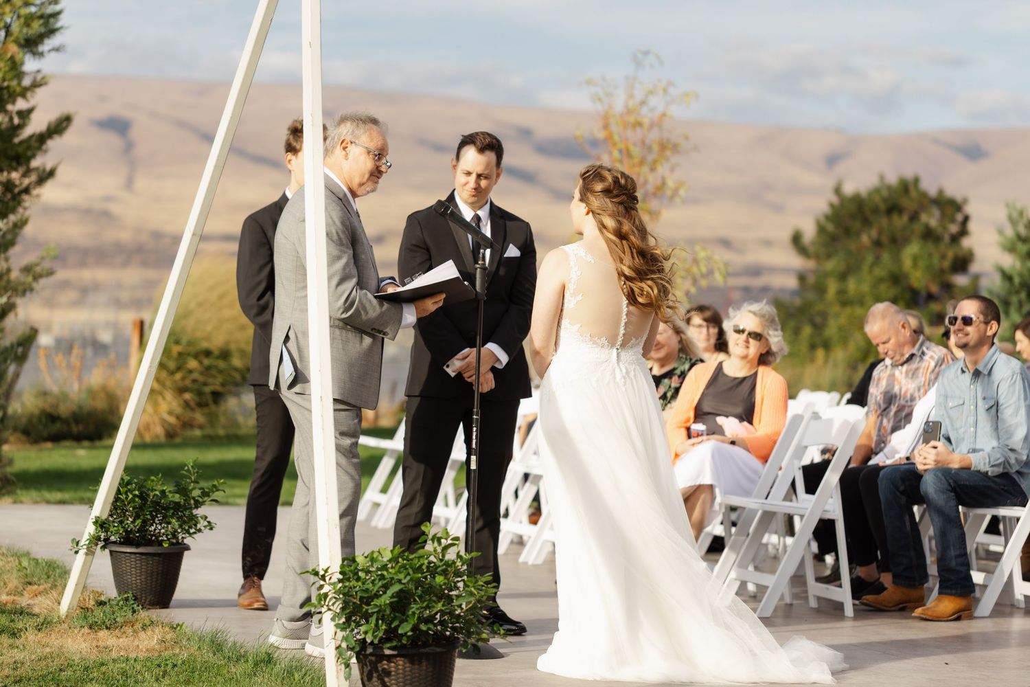 Romantic outdoor wedding ceremony with mountain views and white chairs set up on a grassy lawn.
