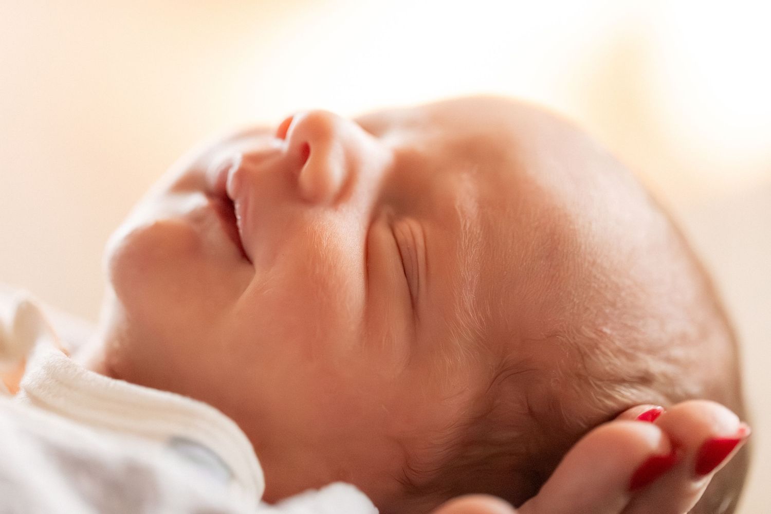 Peaceful newborn baby sleeping with eyes closed, cradled in gentle hands.