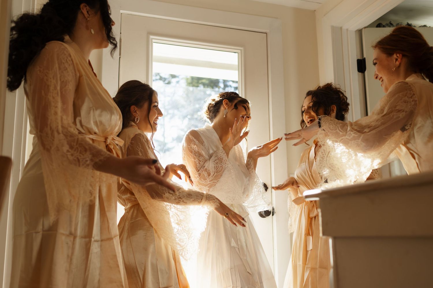A row of ethereal figures in flowing white dresses and veils stand in a sunlit room creating a dreamy atmosphere.