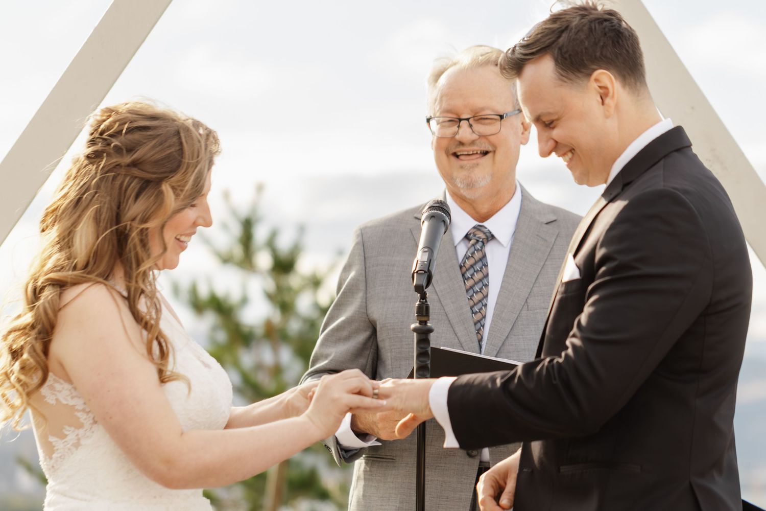 Emotional outdoor wedding ceremony with guests gathered under blue sky.