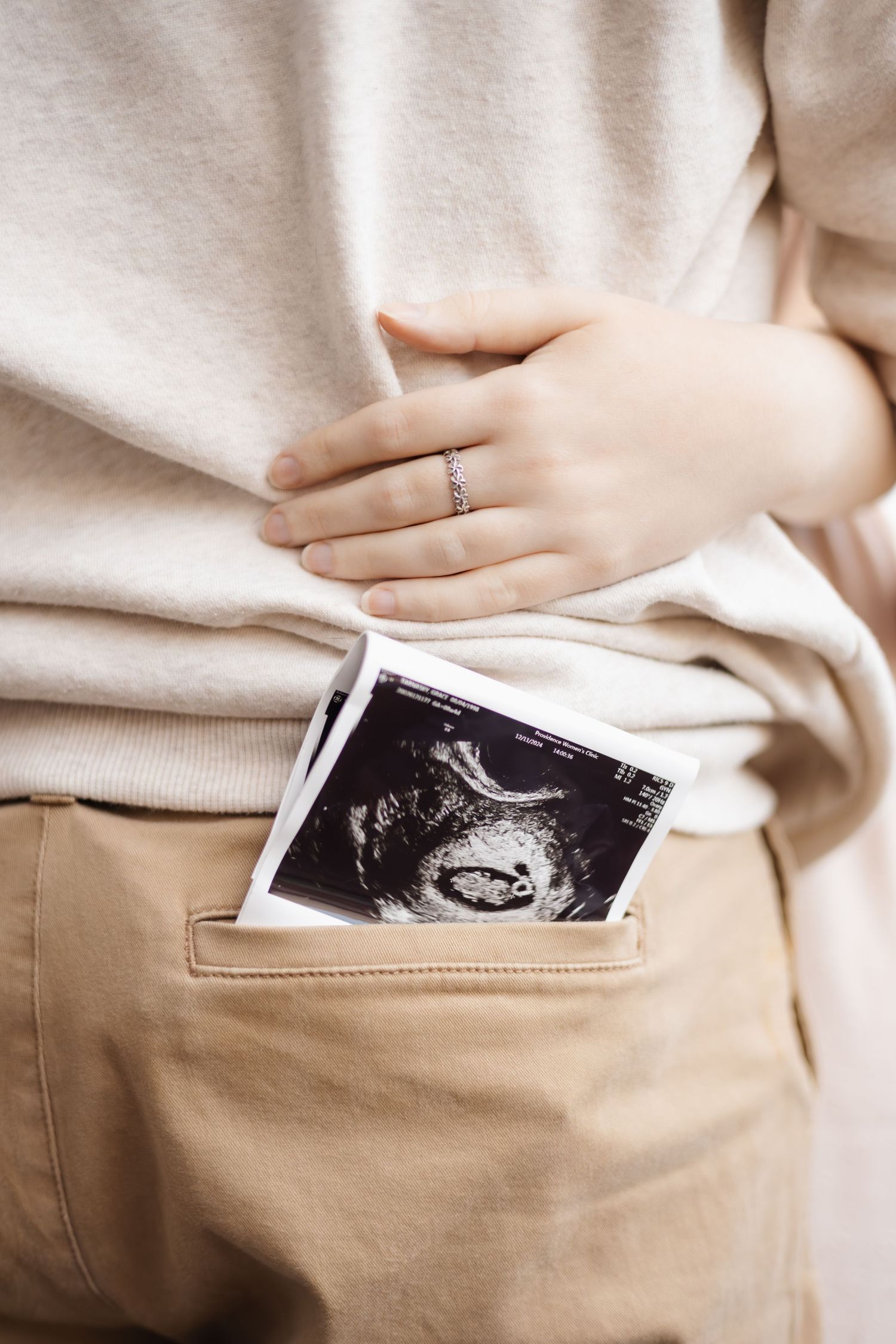 Close up of ultrasound photo being tucked into khaki pants pocket.