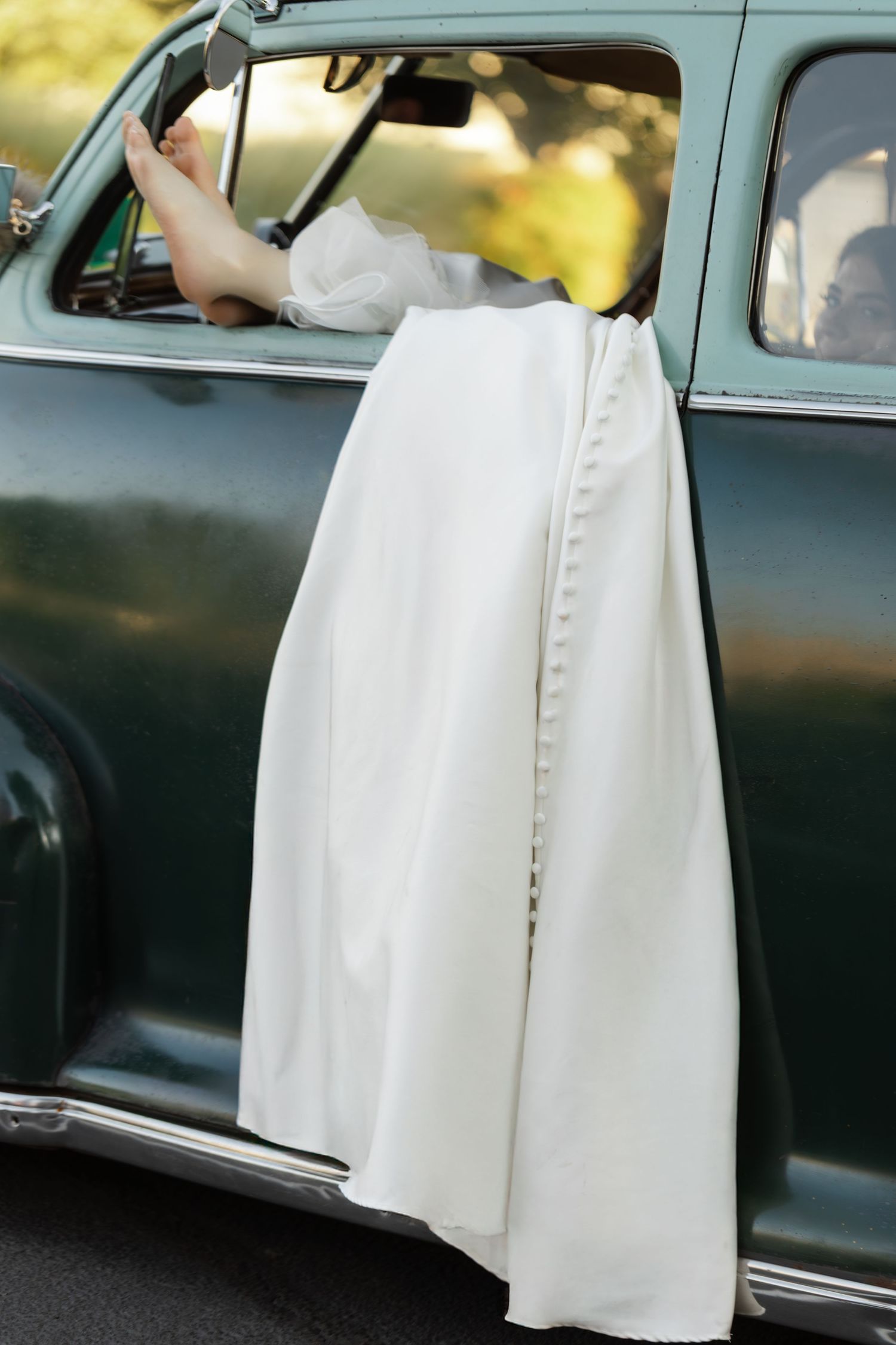 A classic black vintage car with a white-dressed figure entering and exiting in multiple shots.