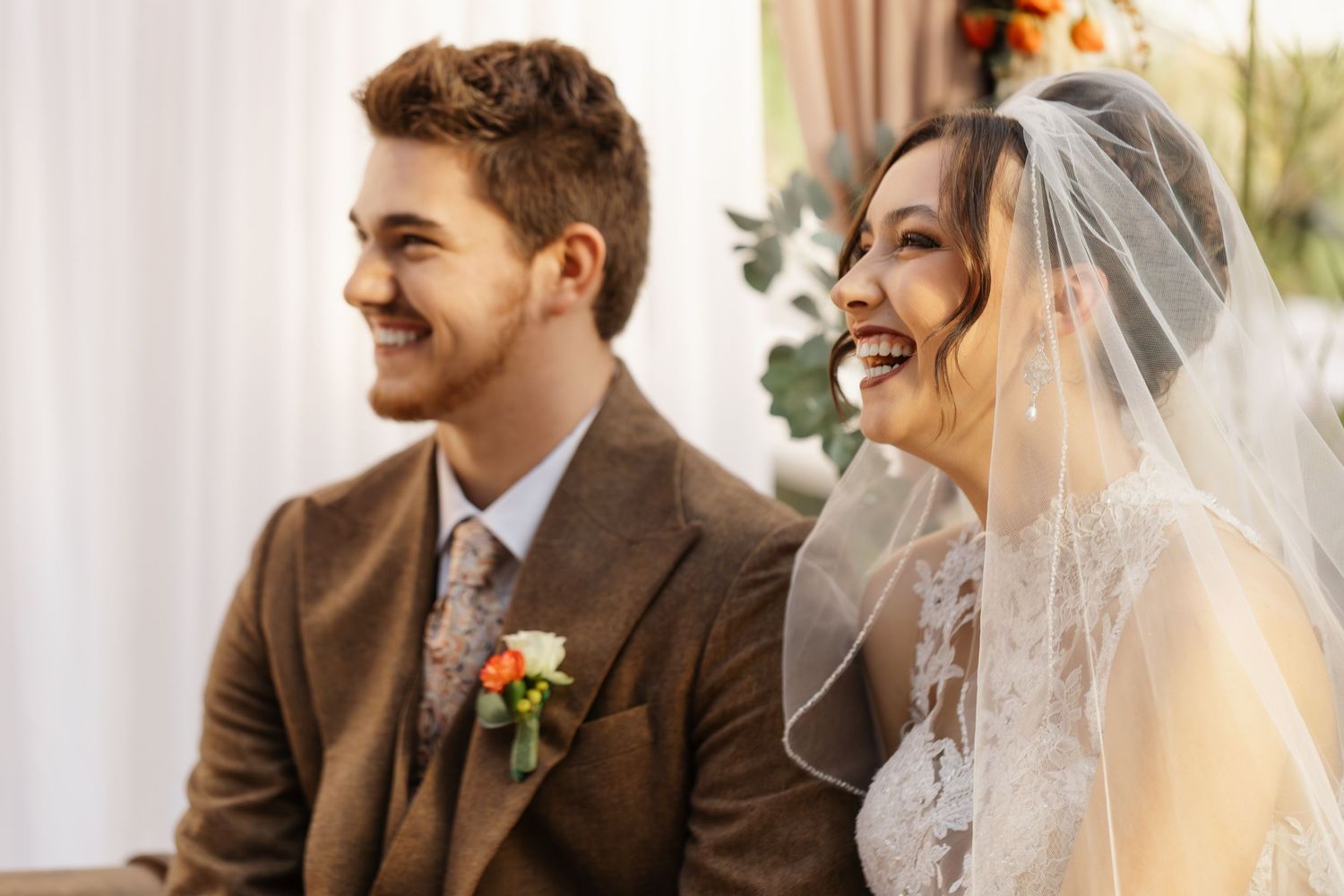 Candid moment of newlyweds sharing laughter during their wedding ceremony.