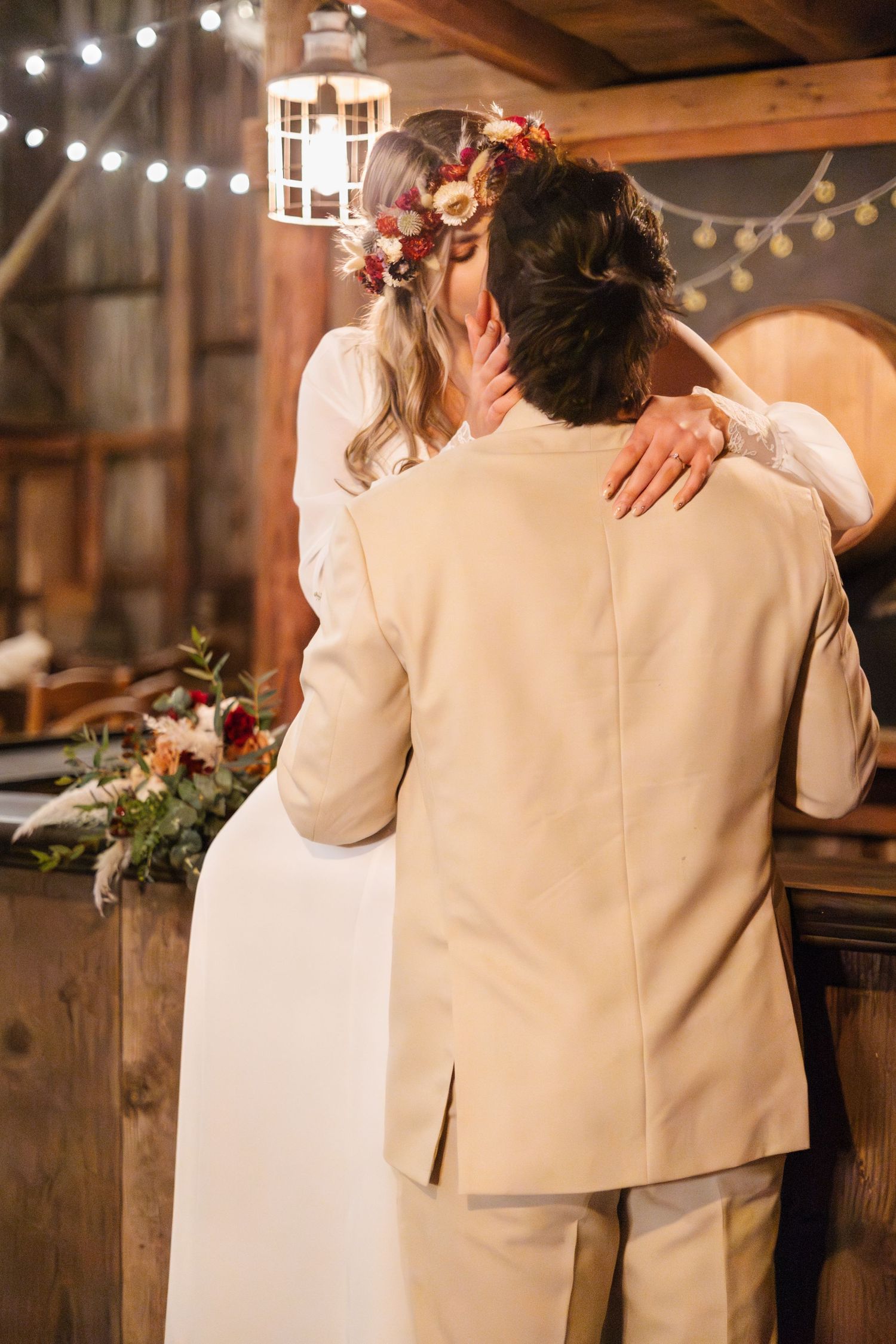Wedding couple dancing in rustic barn venue with string lights overhead.