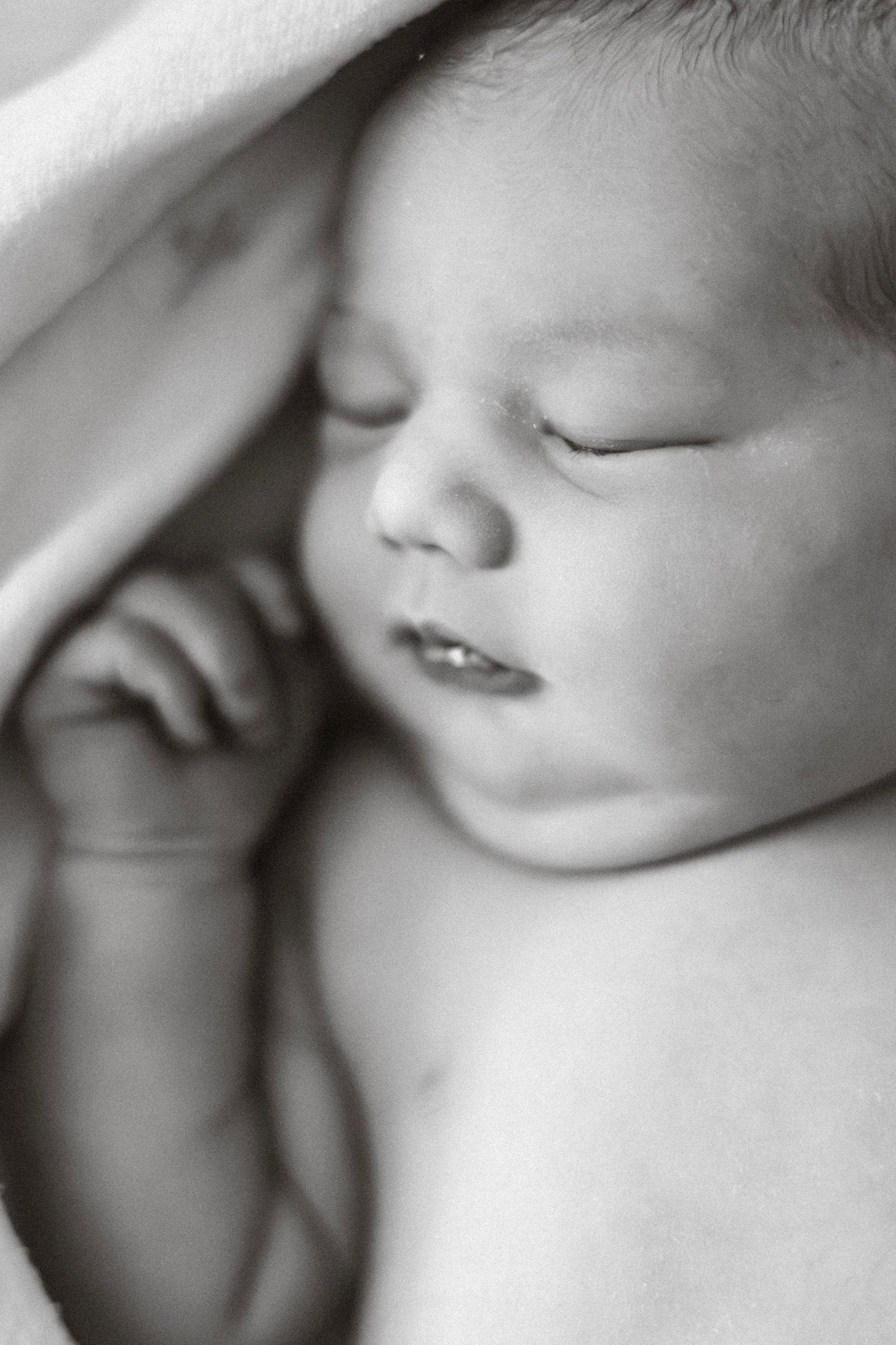 Intimate black and white close-up portraits capturing a newborn's peaceful sleeping features.
