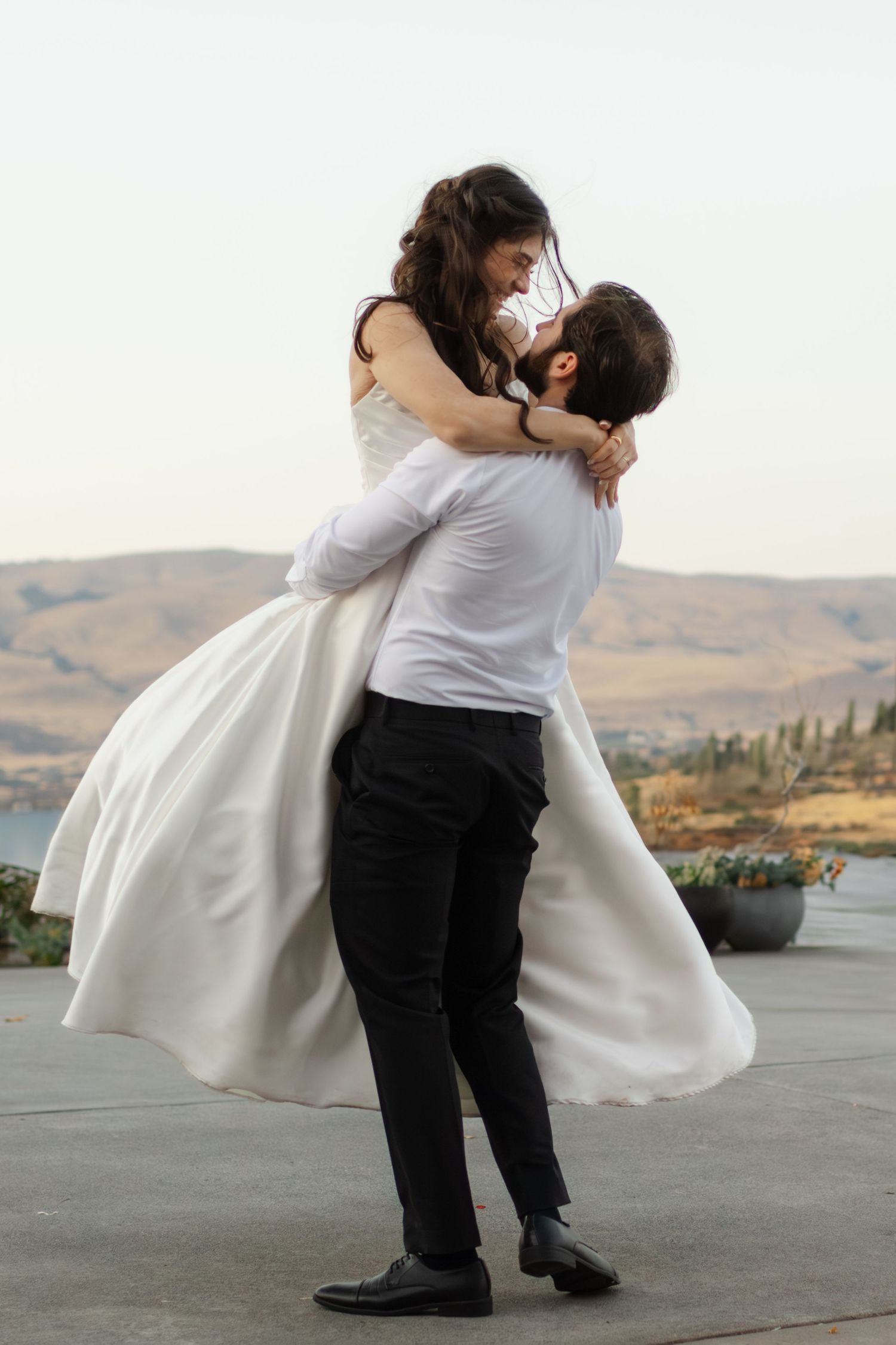 Wedding couple performing romantic dance lift sequence against mountain landscape.