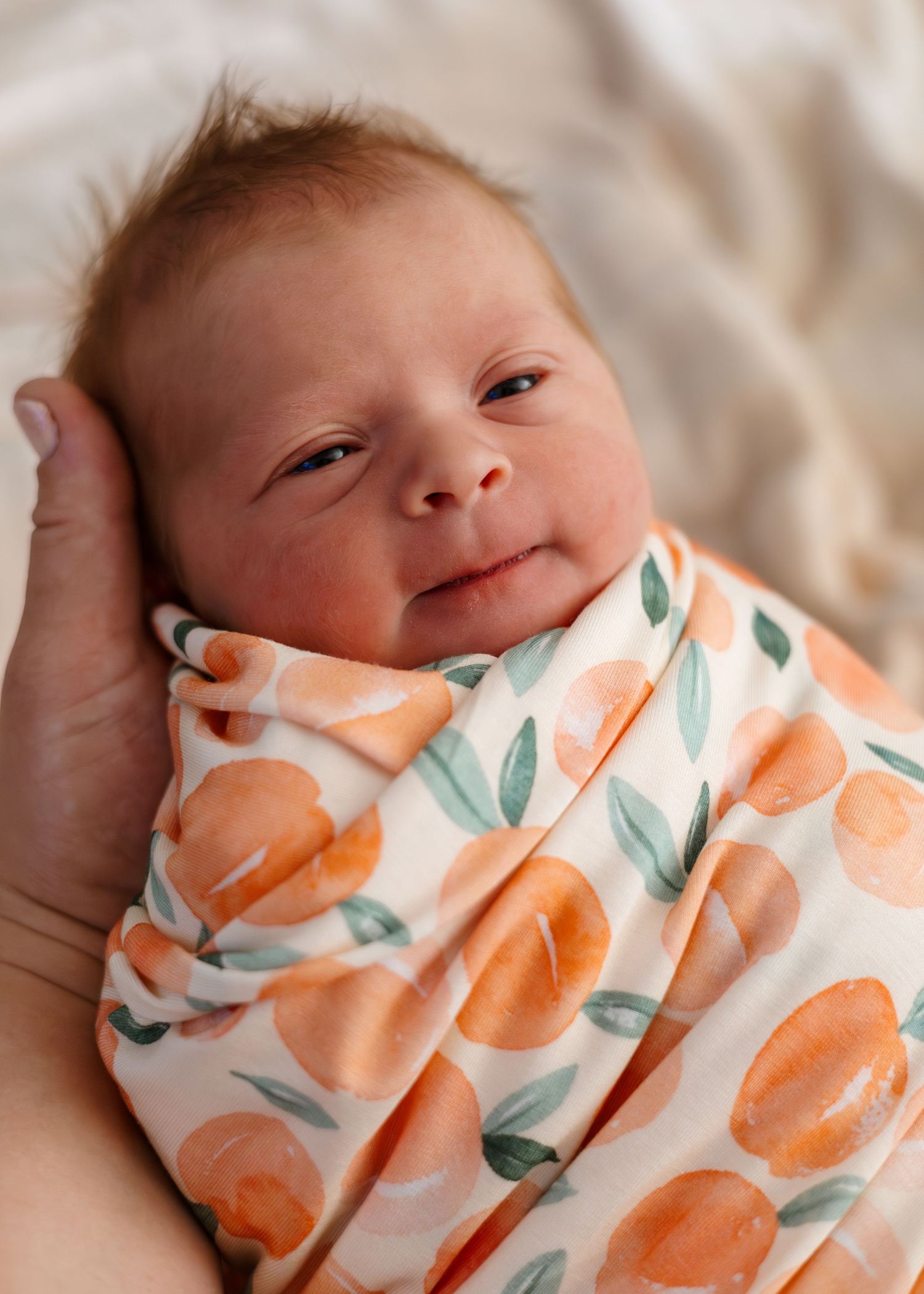 Baby wearing citrus print outfit looking content.