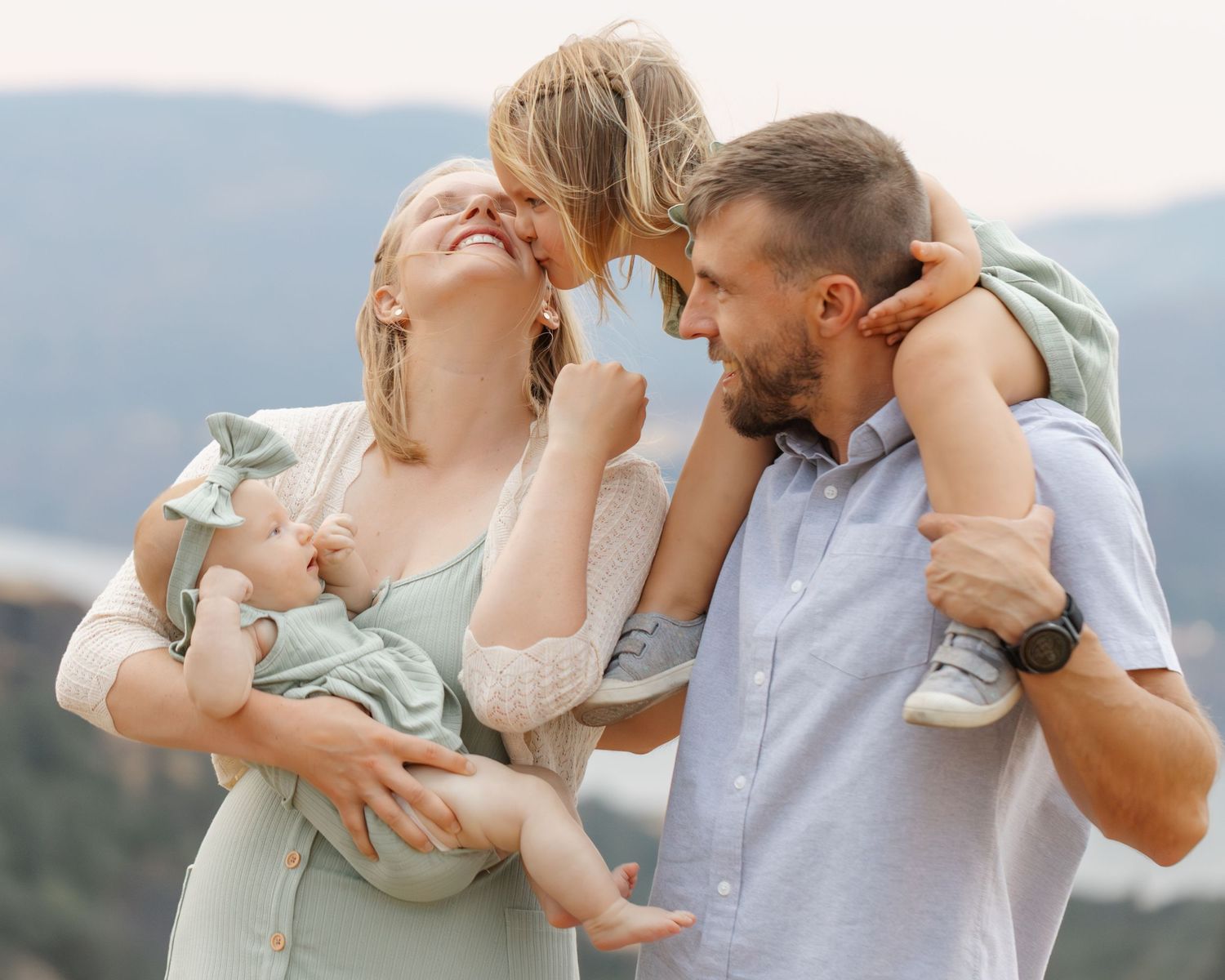 Family sharing intimate moment together on mountain overlook during sunset.