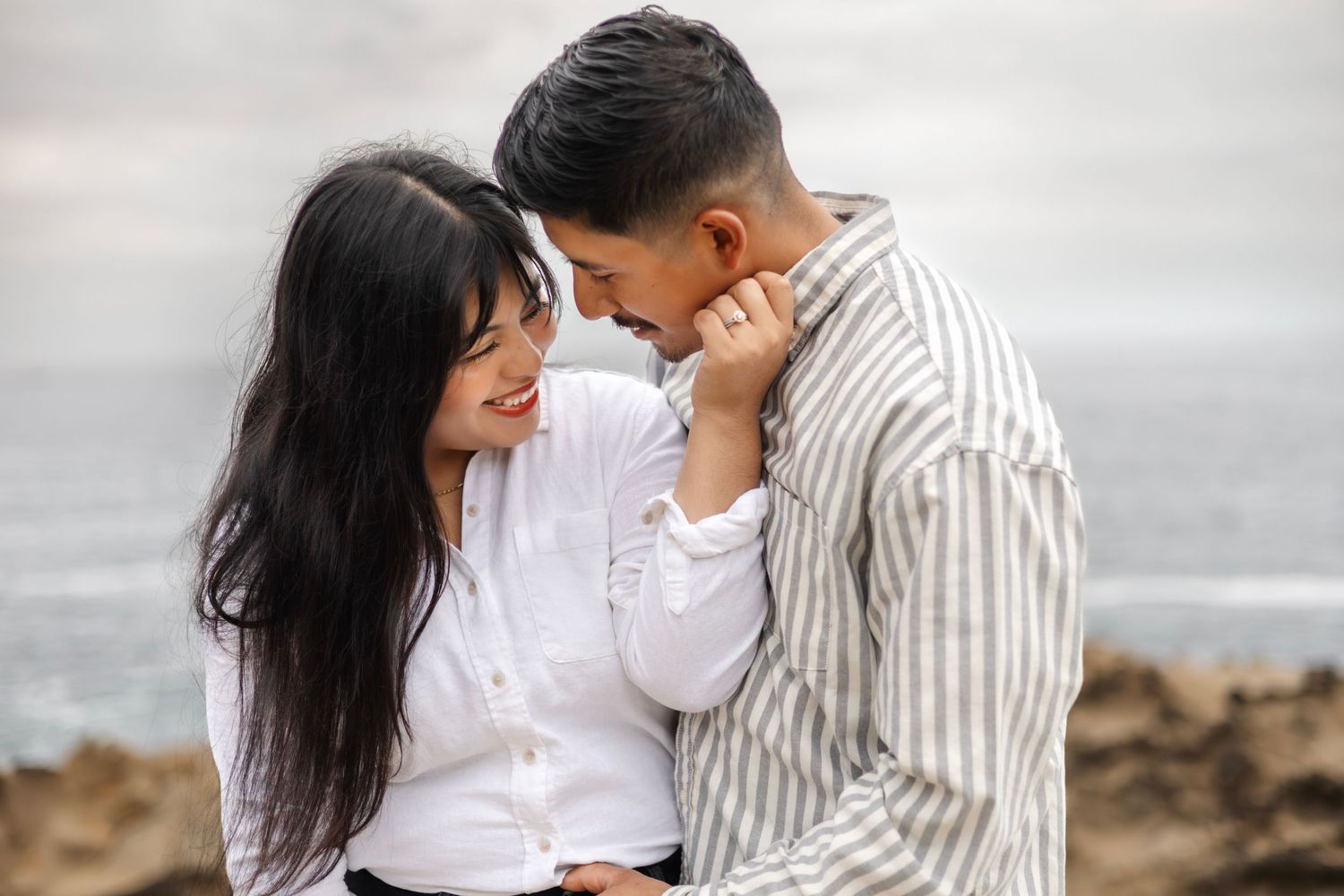 Couple in white and striped outfits sharing intimate moments outdoors.