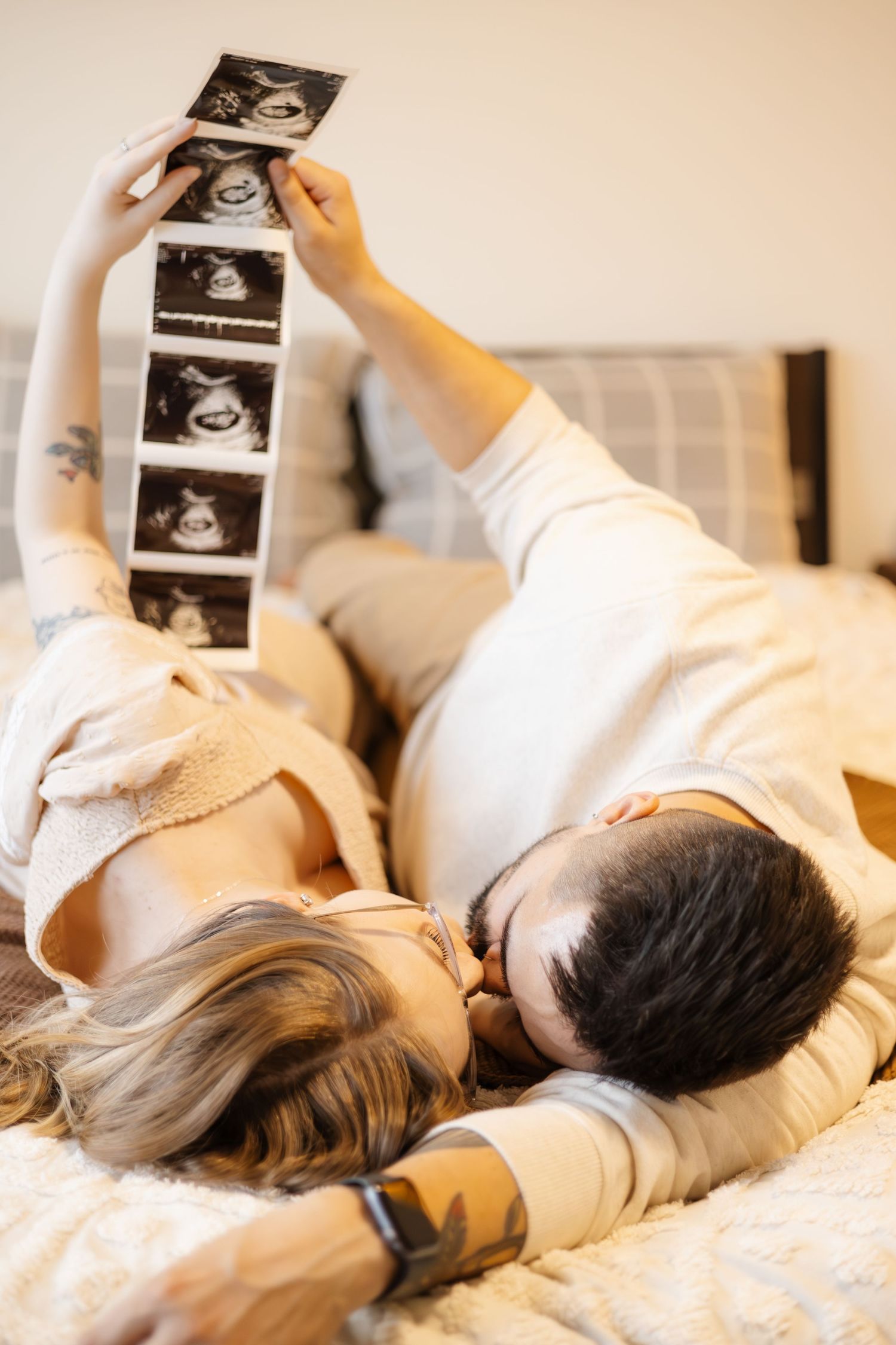 Side view of couple lying on bed examining ultrasound photos together.