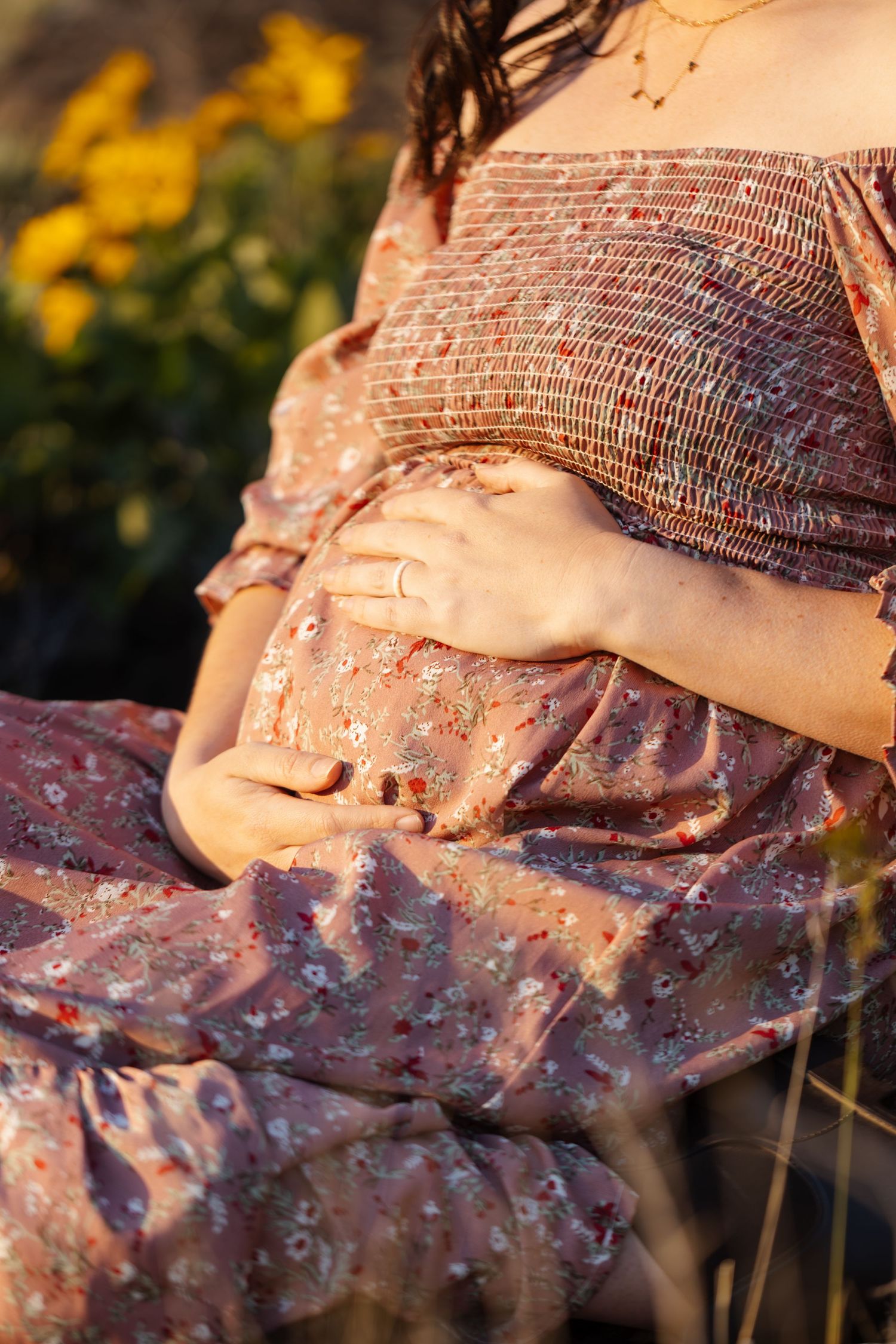 Close-up of smocked bodice detail on pink floral dress in sunset lighting.