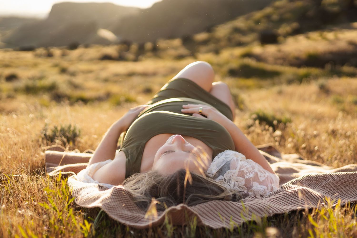 Peaceful moment in golden field during sunset maternity session.
