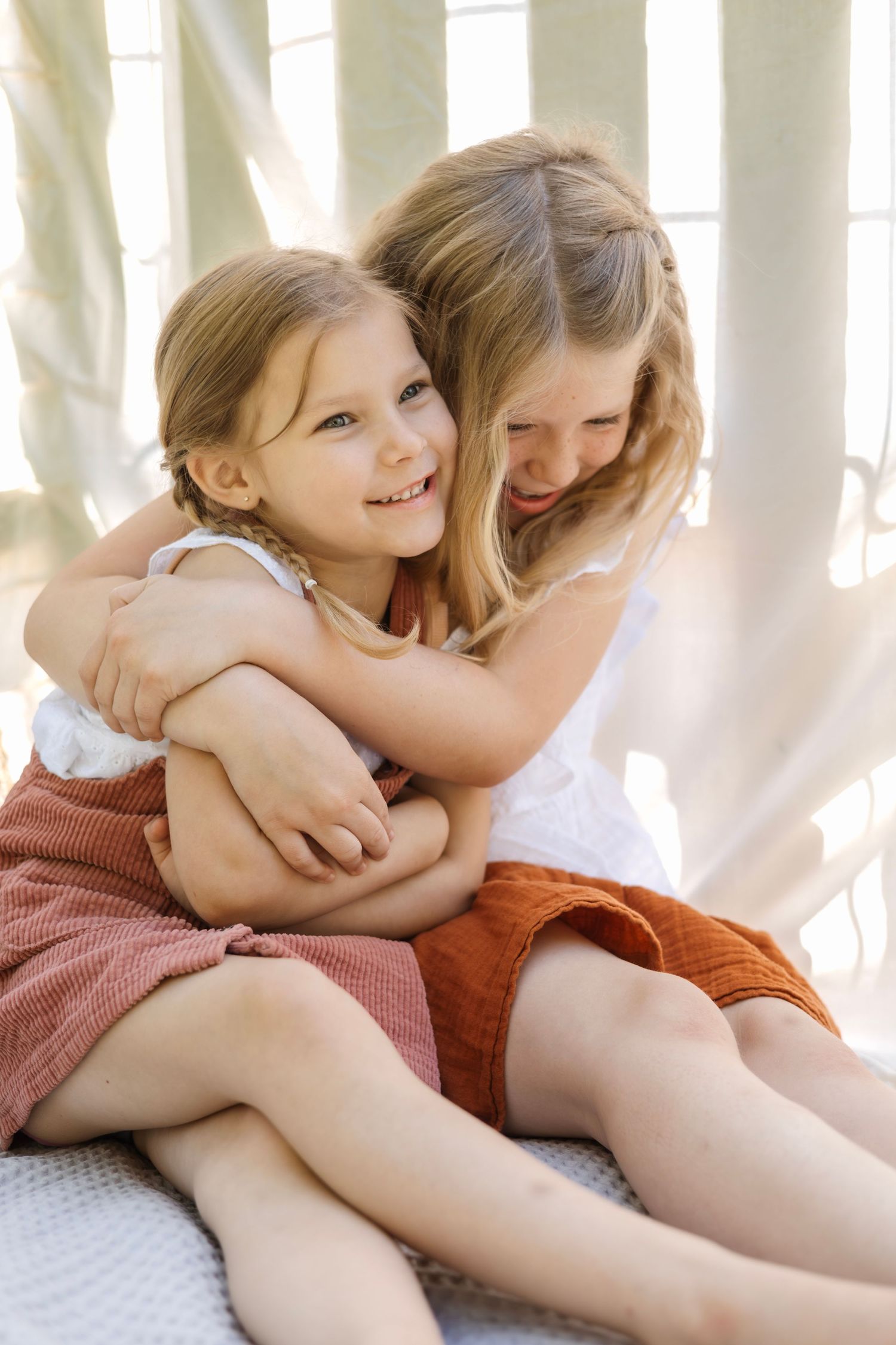 Intimate portrait of siblings sharing tender moment in bright sunlit setting.