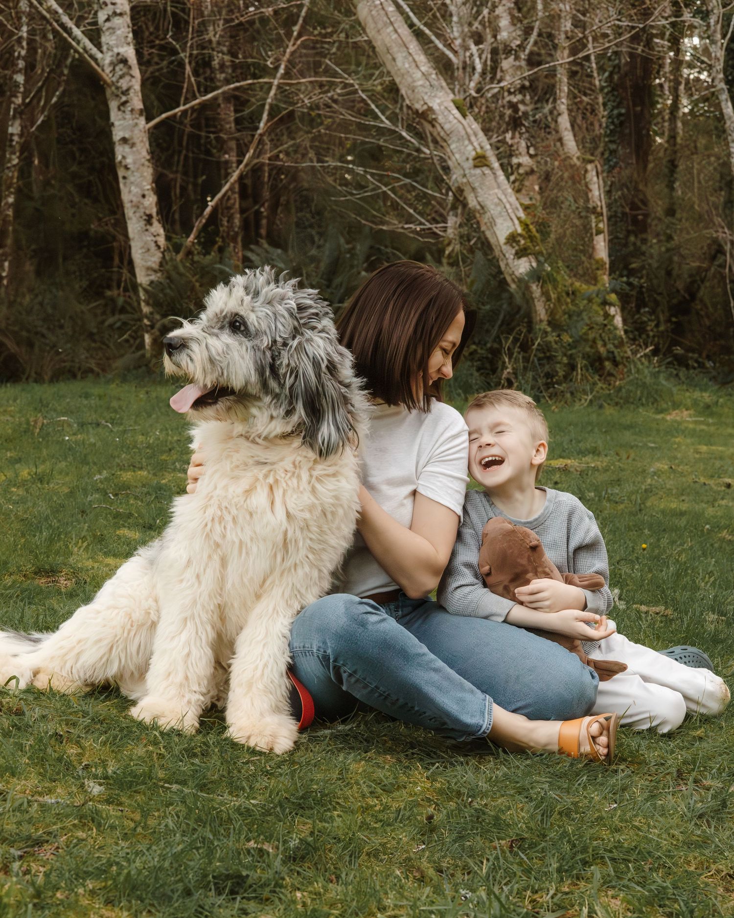Family and their white dog relax together on grass during outdoor photo session.