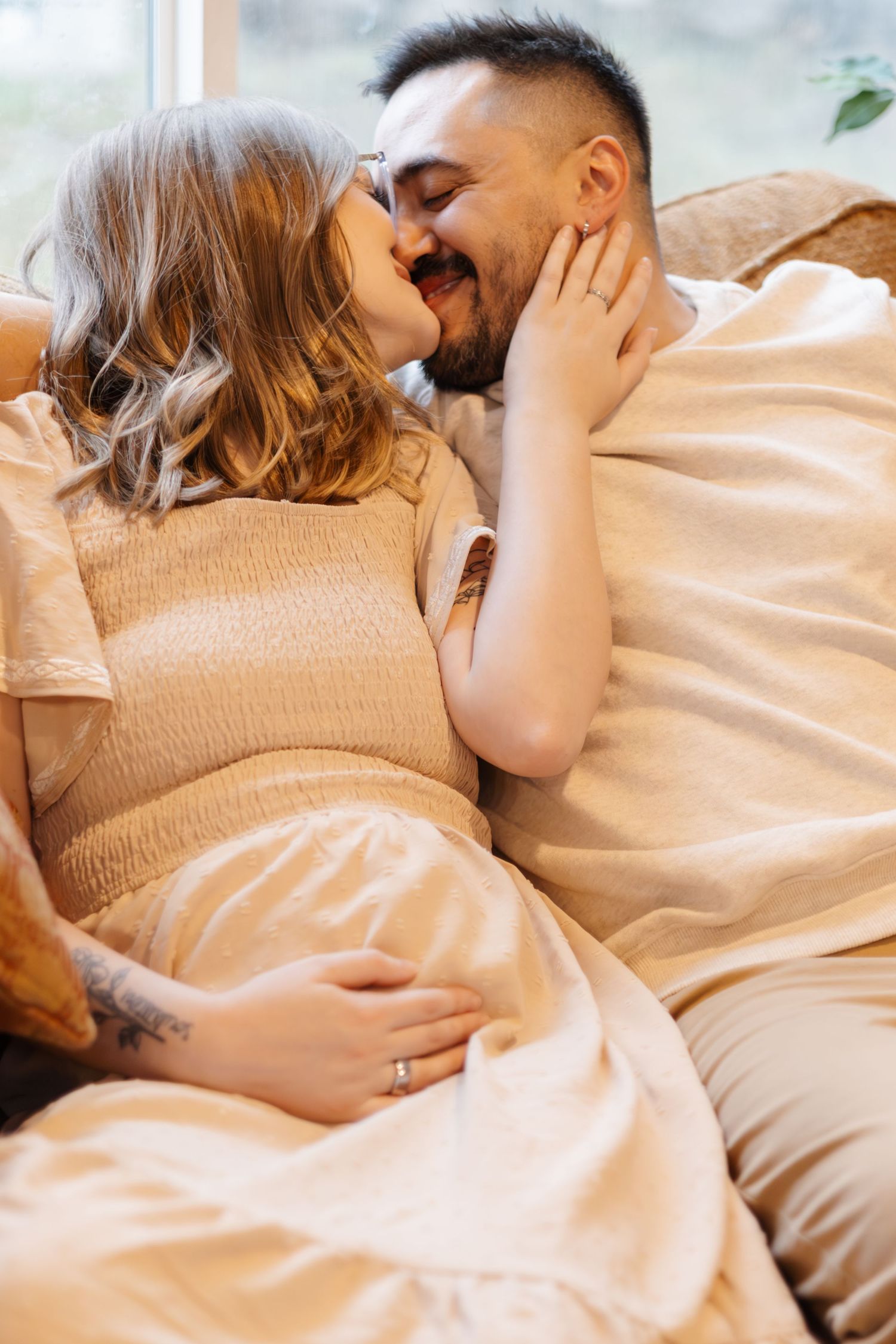 A couple lying together on a bed sharing intimate moments while looking at ultrasound photos.