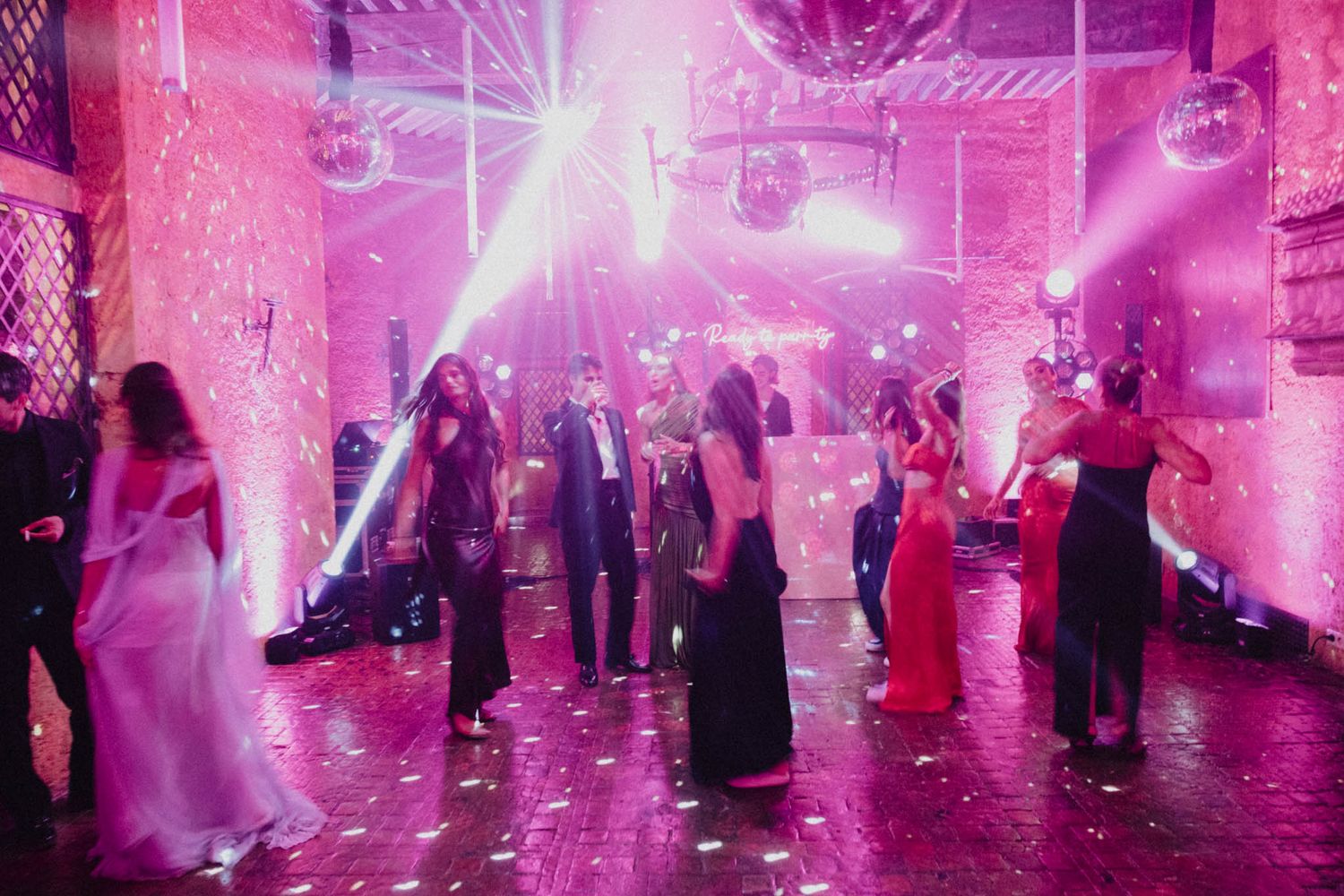 Pink-lit dance floor filled with party guests enjoying a lively celebration with fog effects.