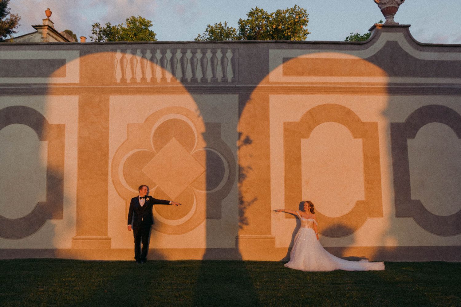 Creative wedding photo with couple silhouetted against orange-lit architectural arches.