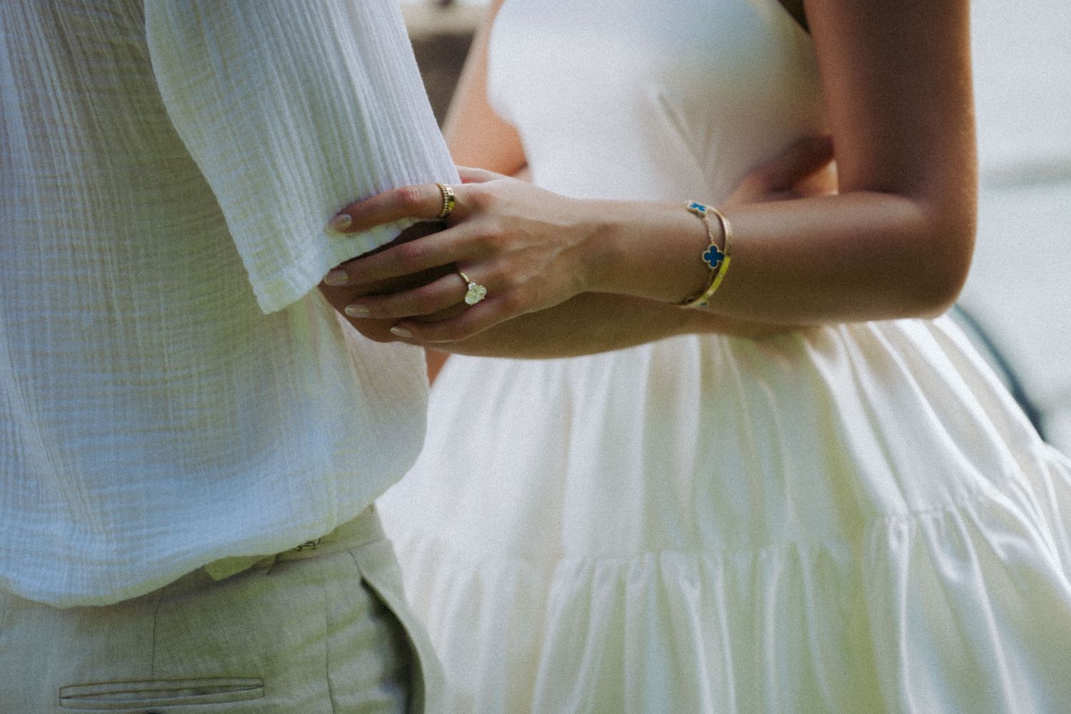 Close-up view of hands holding a white wedding dress fabric showing delicate details and texture.