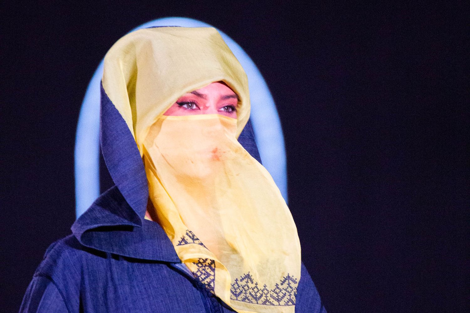 Woman wearing yellow hijab and dark clothing poses in various angles against black background.