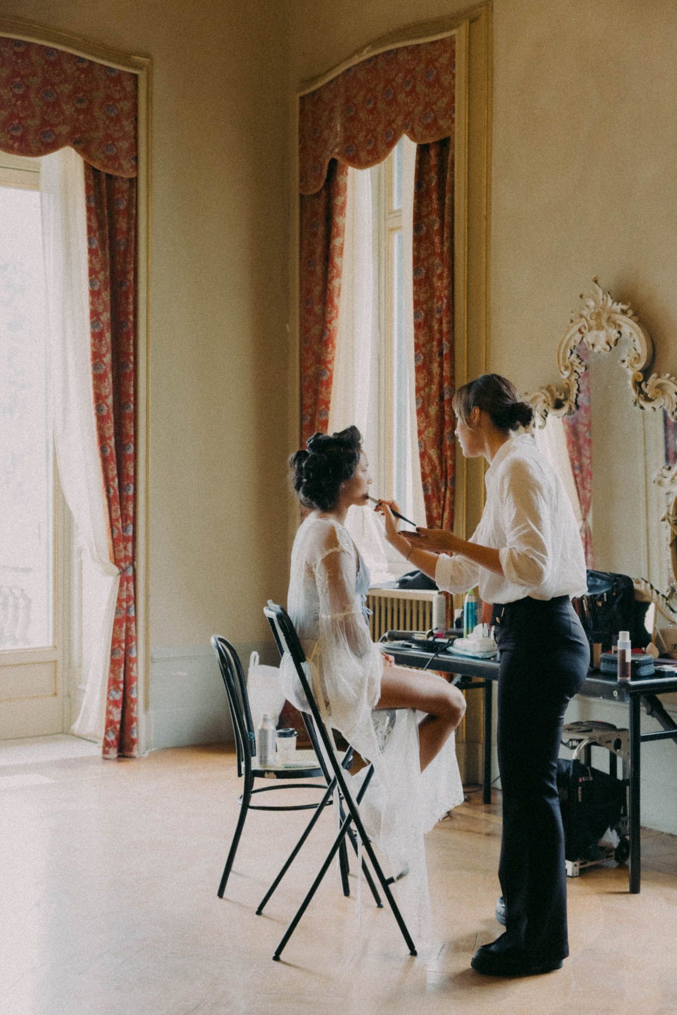 A series of artistic photographs showing figures in black and white dresses seated in an elegant room with floral curtains.