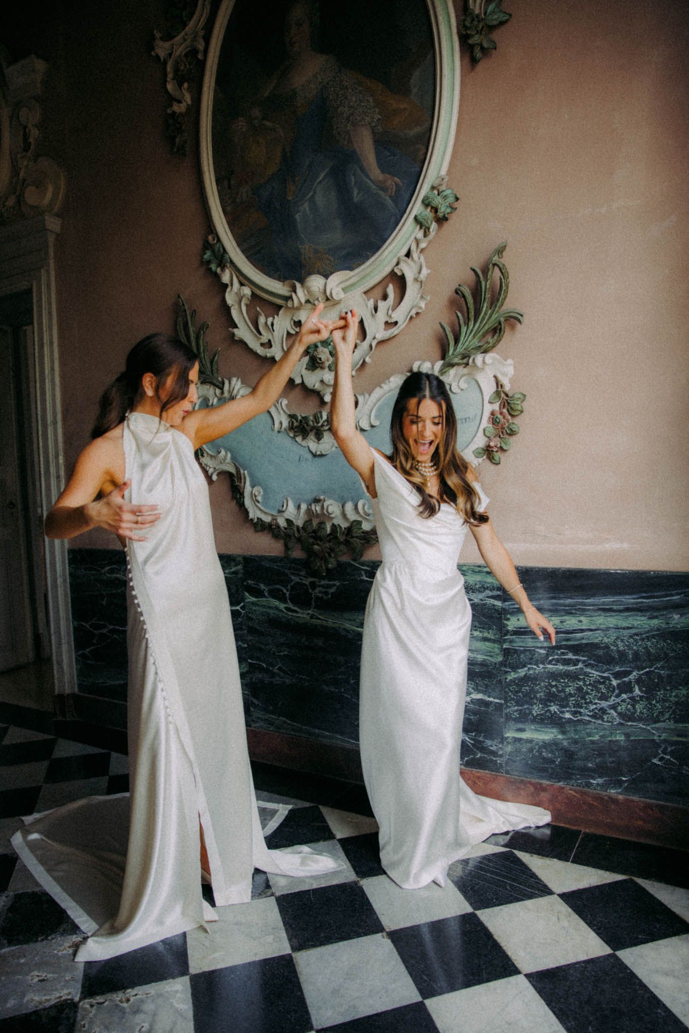 A person in a white dress dances playfully in a room with checkerboard floors and ornate mirrors.