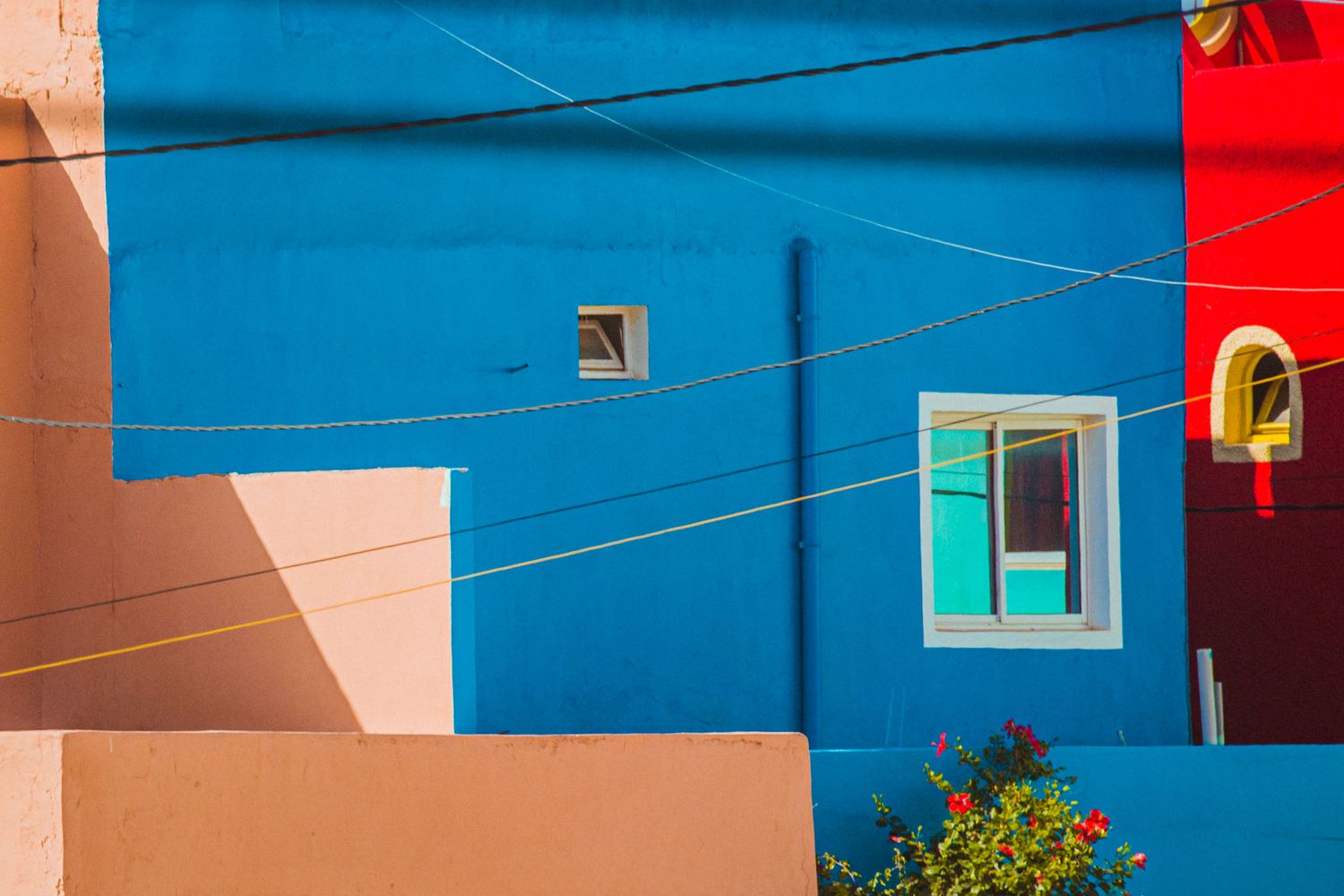 Colorful residential buildings with bright blue and red walls create a vibrant architectural scene in a sunny neighborhood.