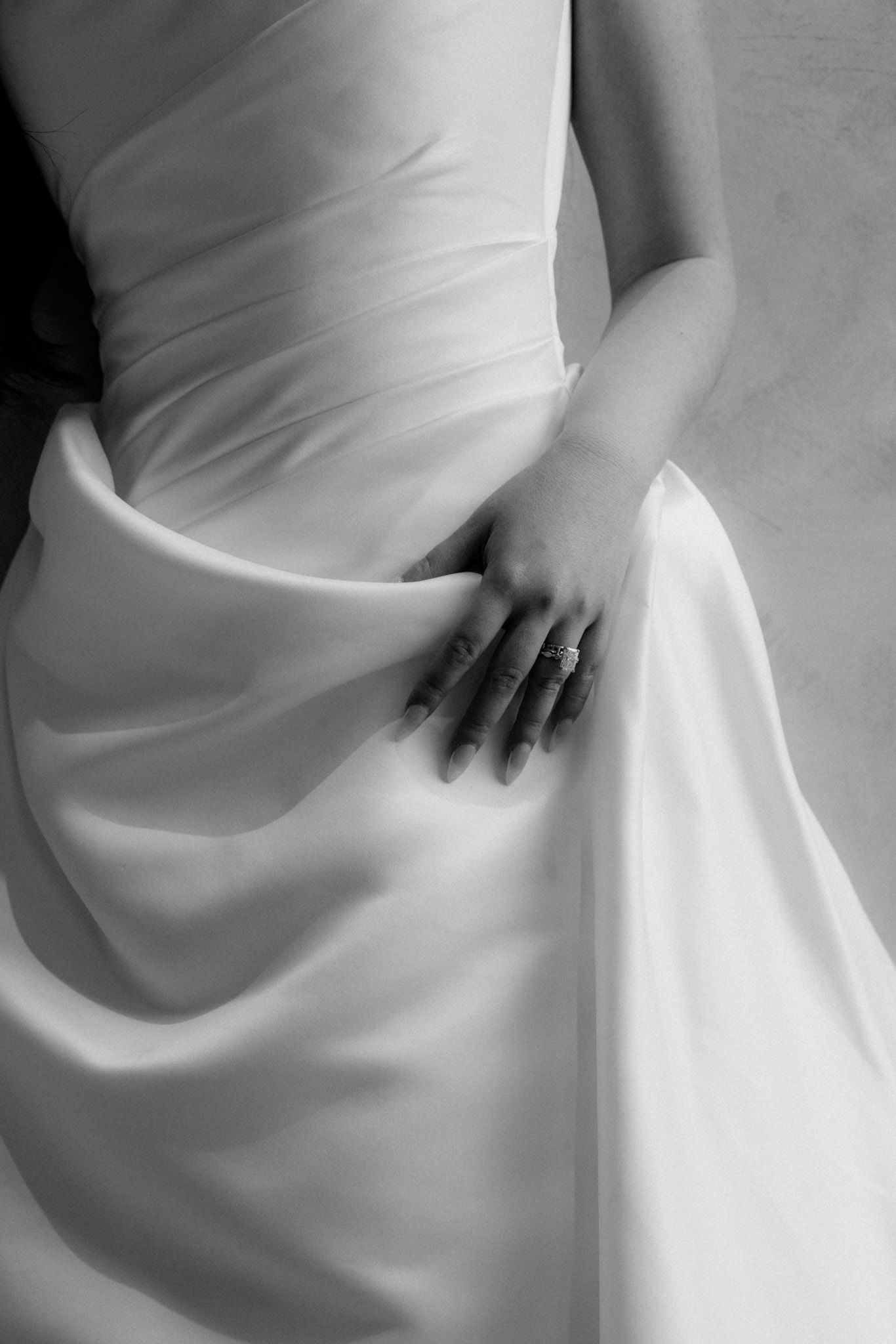 A series of minimalist black and white photographs showing flowing white fabric with hands creating gentle folds and movement.