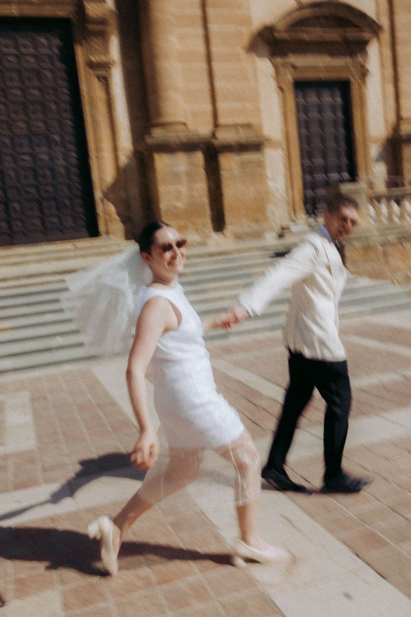 A sequence of dance-like movements captured in motion on stone steps outside a historic building.