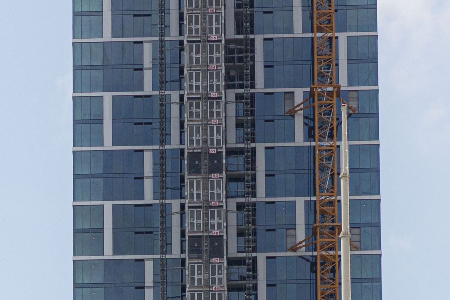 Geometric patterns of windows and balconies on a modern blue-glass residential high-rise building.