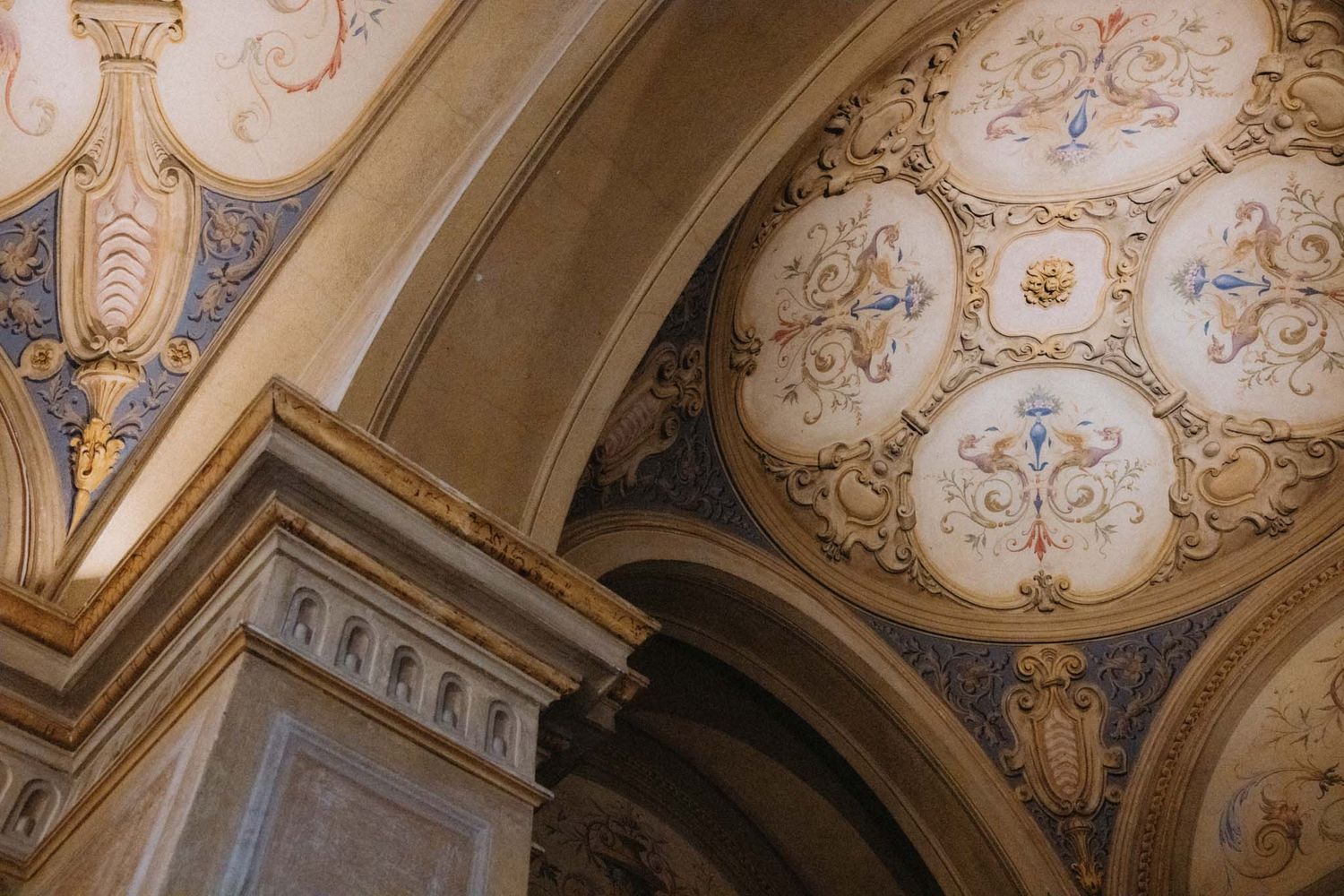 Ornate baroque ceiling with intricate gold leaf details and painted medallions in a historic European palace.