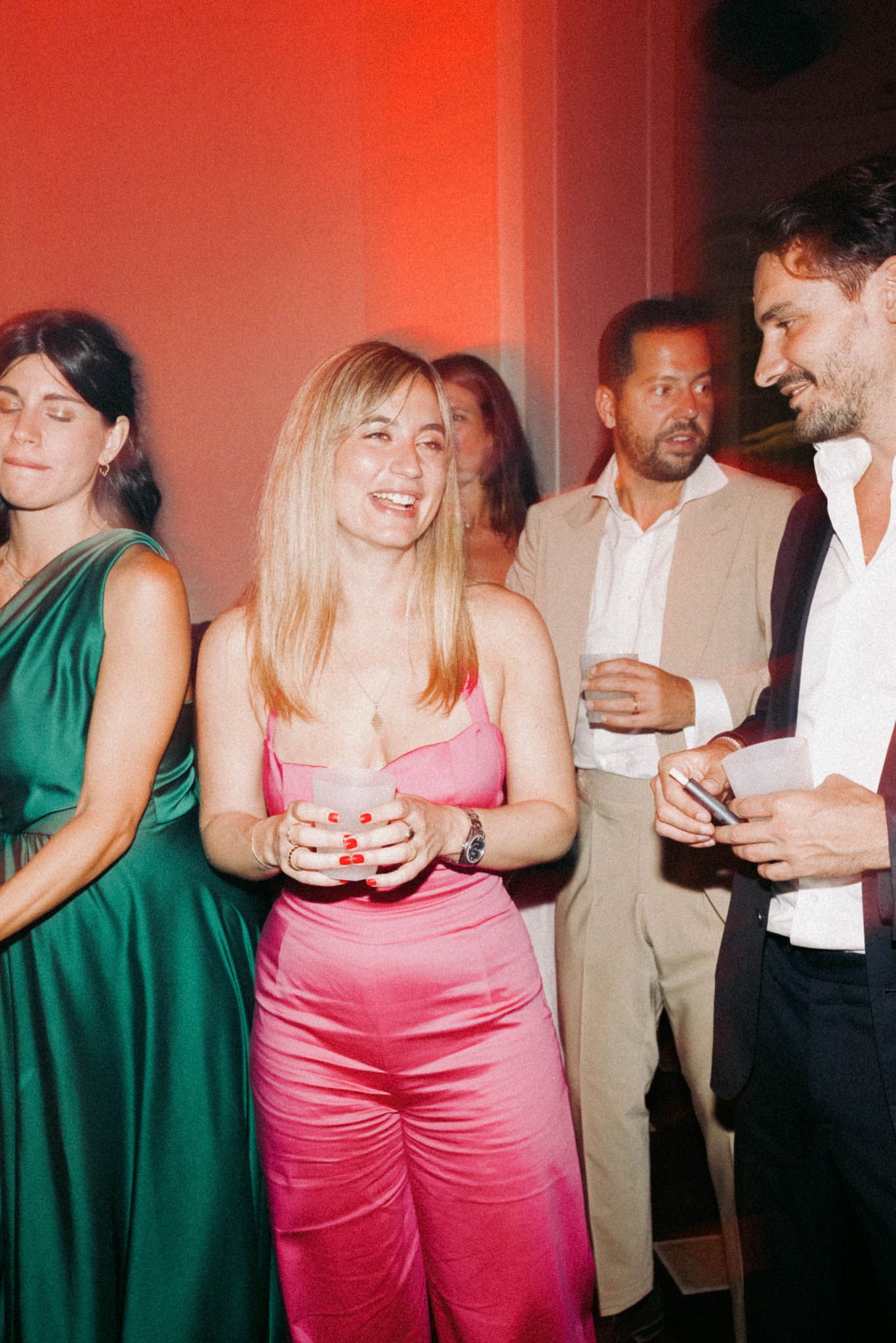 People in formal attire socialize at a party with pink and green dresses visible in the cropped photo series.