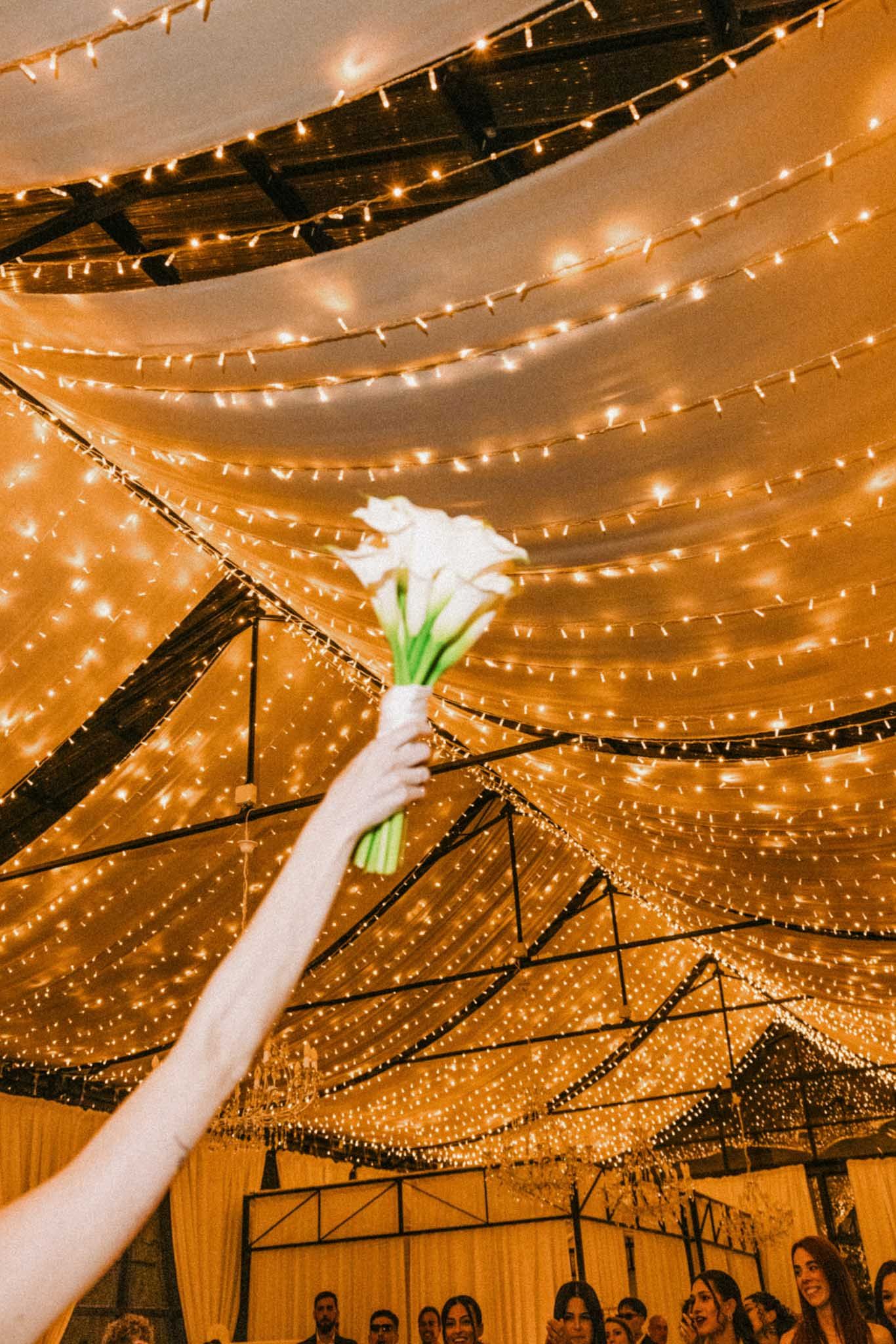 String lights create a magical canopy over an indoor reception venue with a warm amber glow.