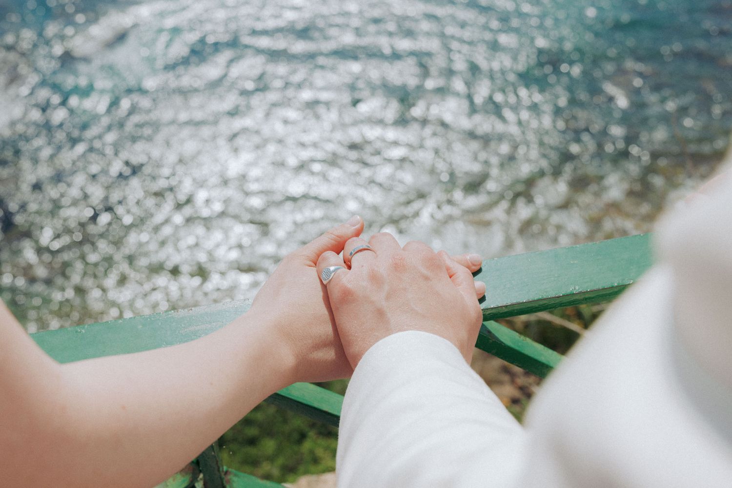 A hand reaches out to touch the sparkling turquoise ocean water from above while sailing on a boat.