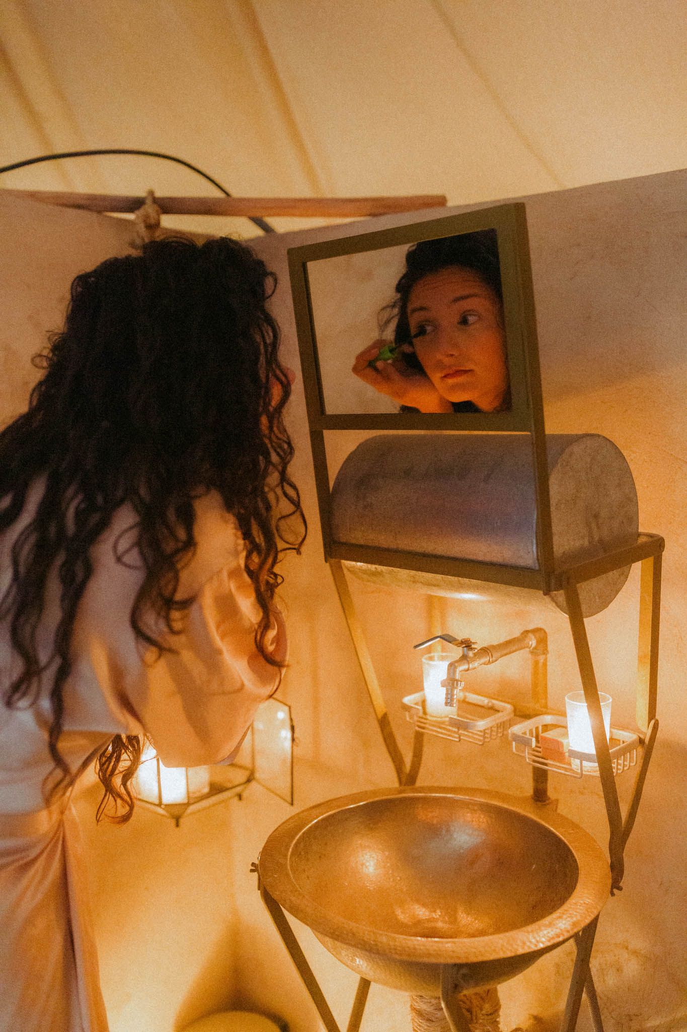 A candlelit scene with curly hair silhouetted against warm glowing light and hanging glass fixtures.