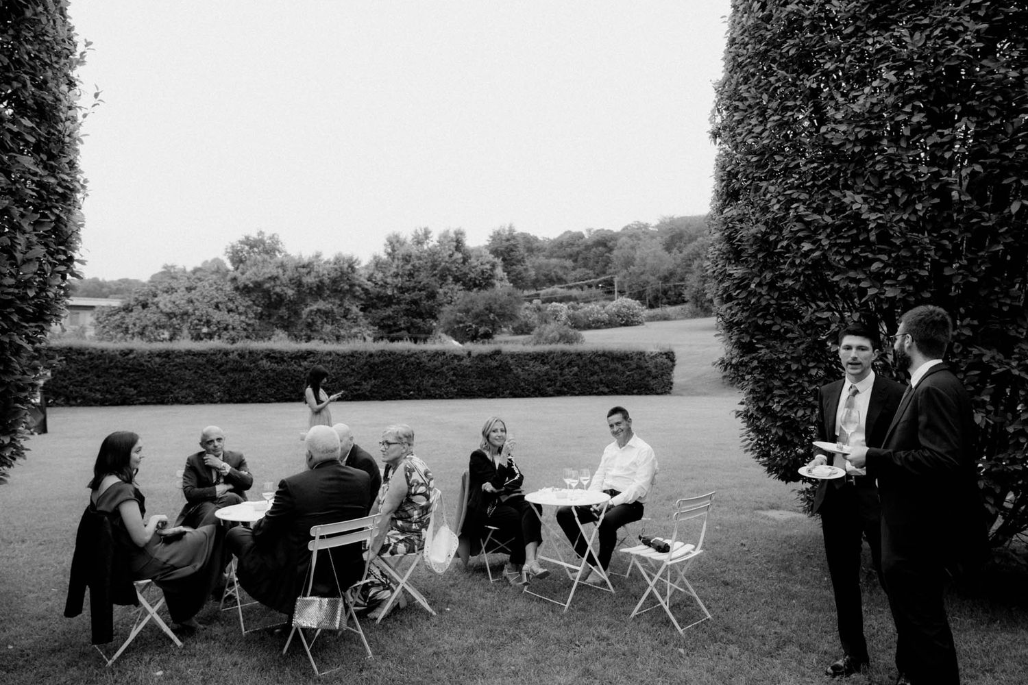 A series of black and white photographs showing people sitting in director's chairs on an outdoor lawn.