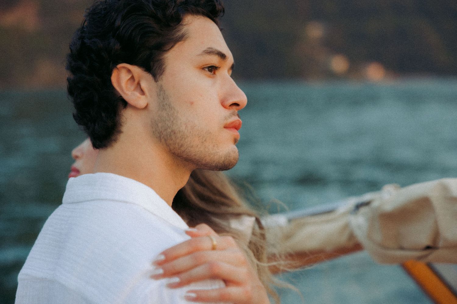 A couple sits together on a boat deck enjoying a romantic moment on the water during sunset.