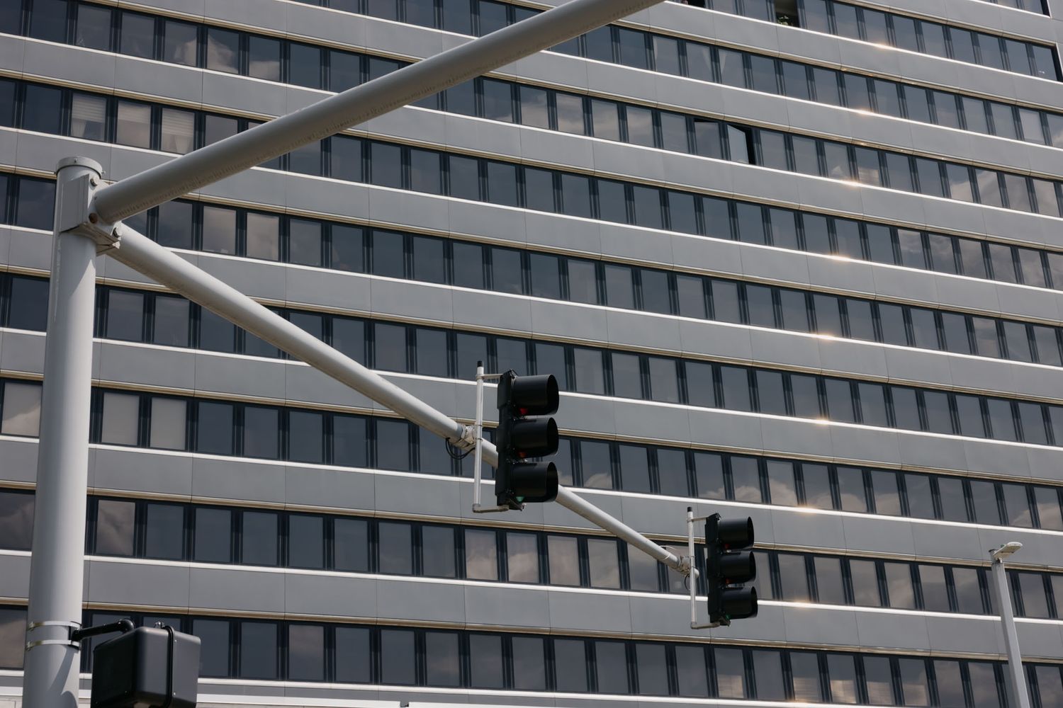 Geometric pattern of white metal beams and supports creates an abstract architectural design against a building facade.