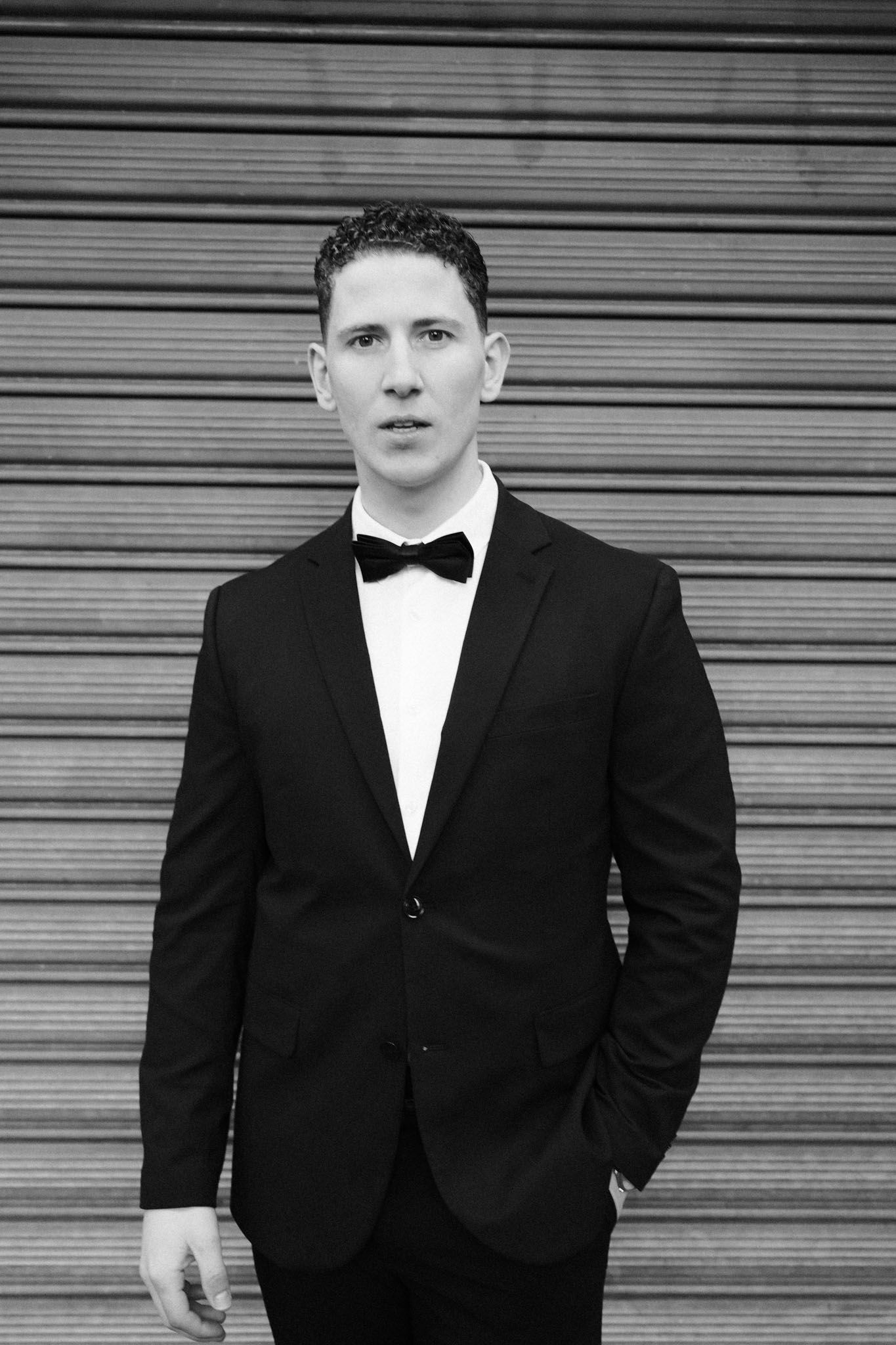 A series of black and white portraits showing a person in formal attire against a metal shutter background.