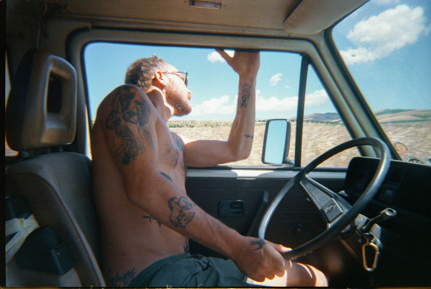 Interior view of a car dashboard and windshield while driving through a desert landscape.