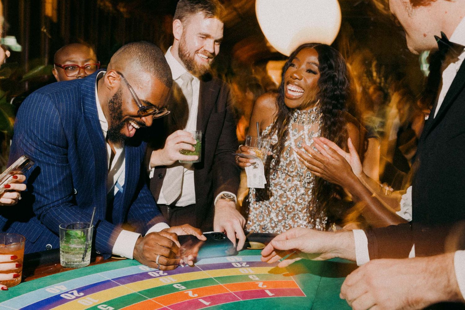 People enjoy playing casino games at tables with colorful chips and cards in an elegant evening setting.
