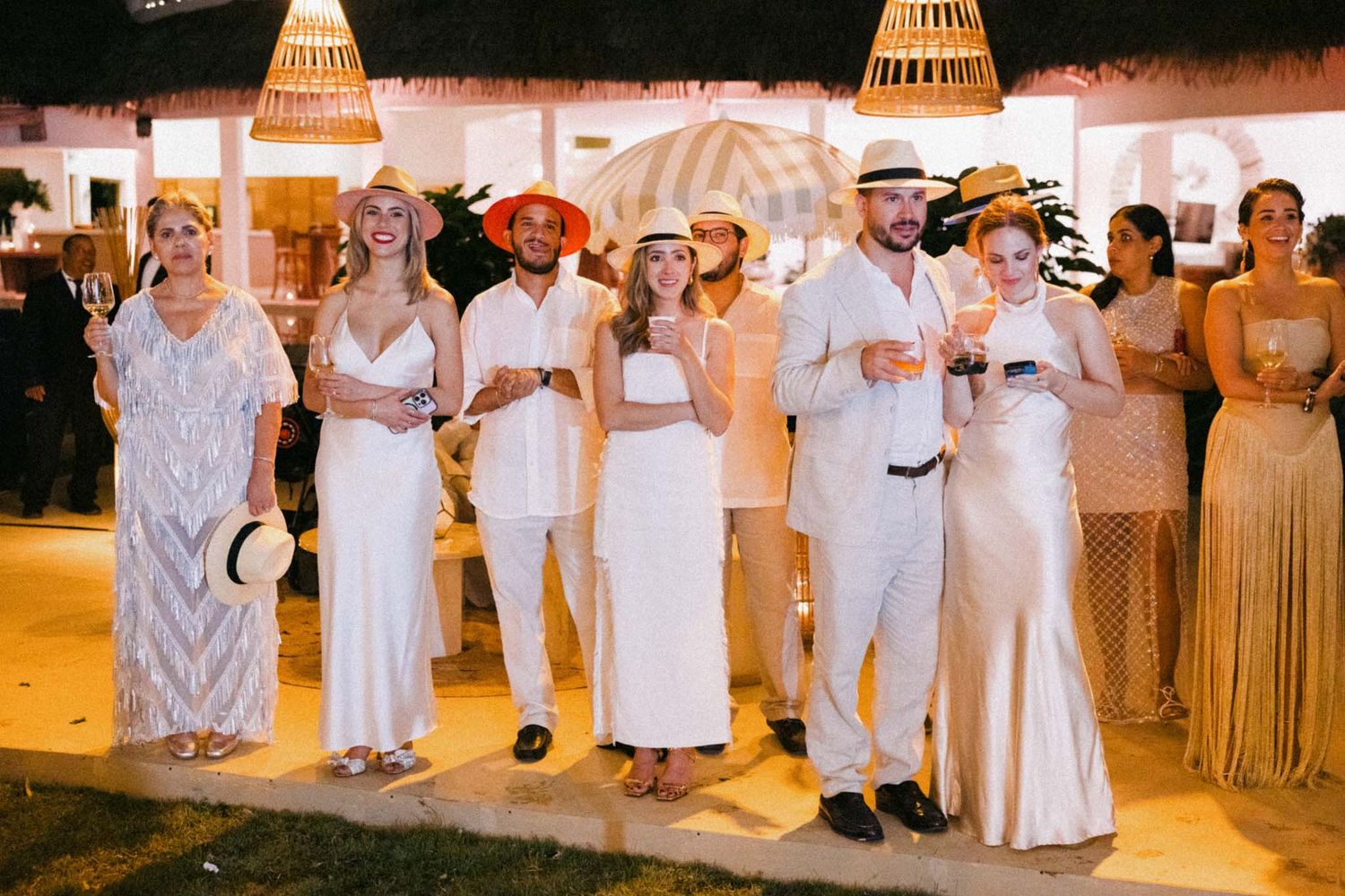 Wedding guests dressed in all white outfits dance together at an elegant reception celebration.