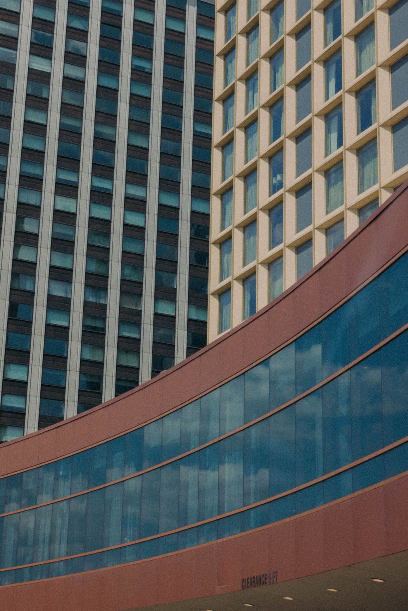 Modern office building facade with curved architectural elements featuring glass windows and reddish-brown accents.