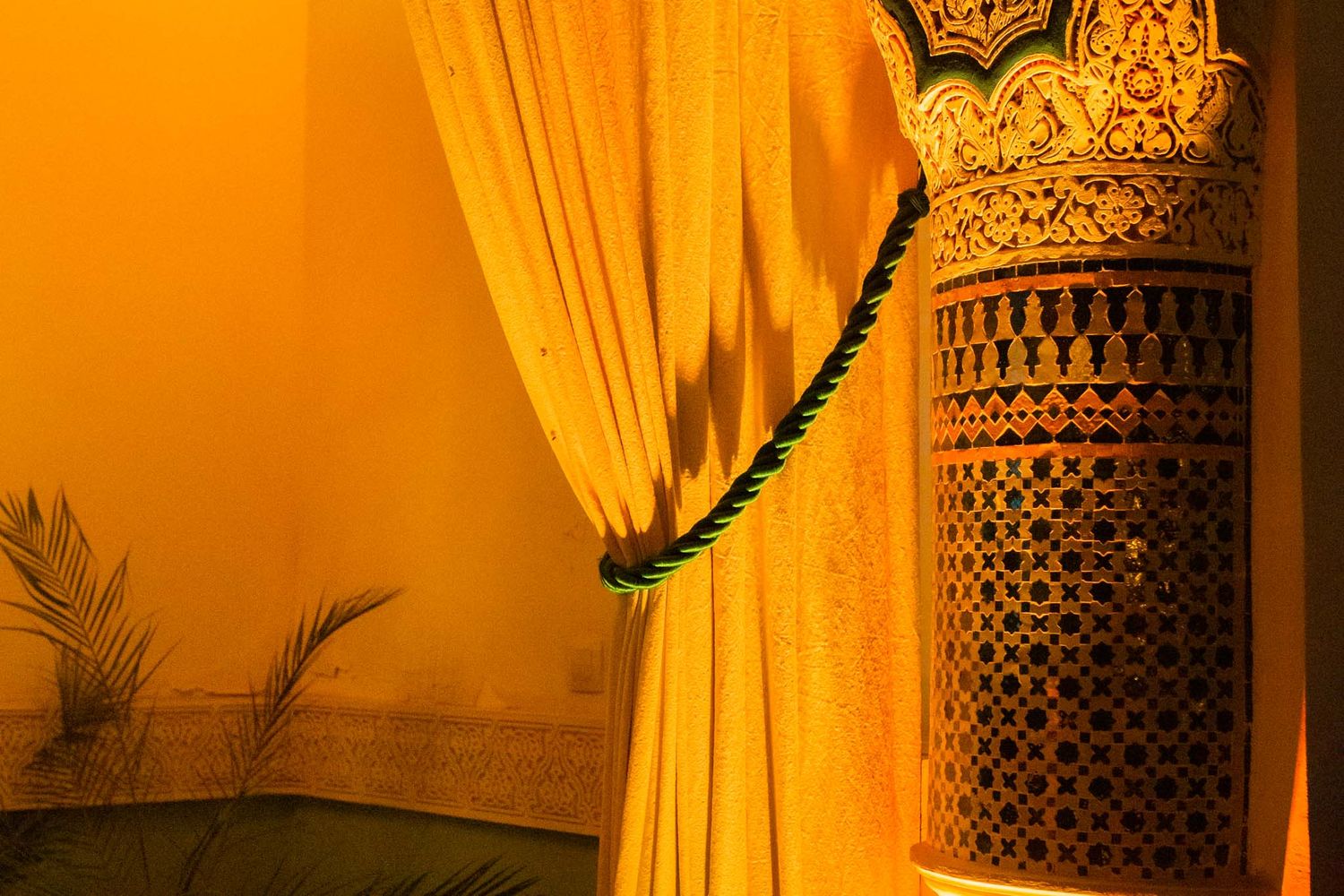 Luxurious spa room interior with warm amber lighting, decorative lanterns, and golden curtains creating a relaxing ambiance.