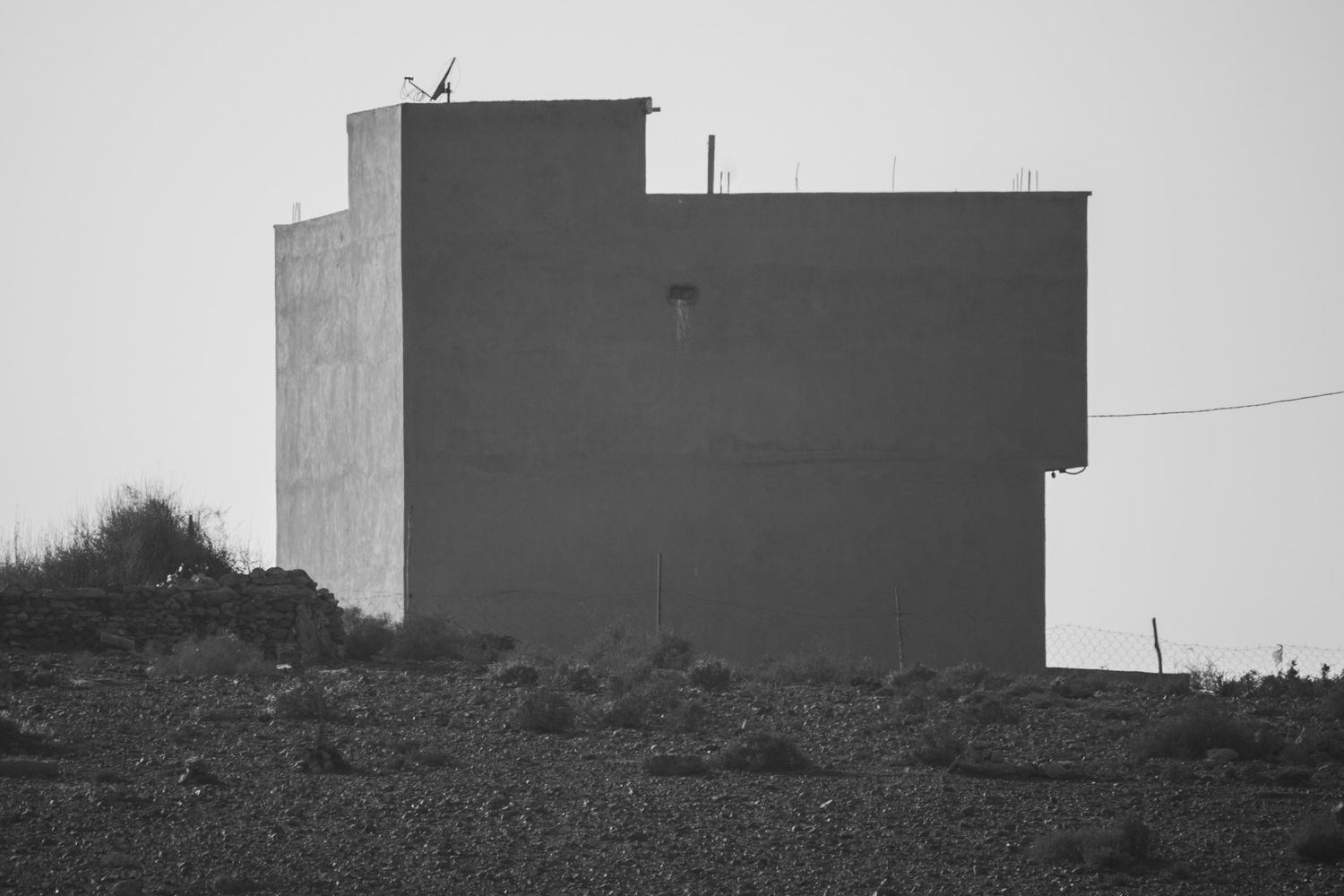 Minimalist black and white landscape with architectural silhouettes against a misty sky.