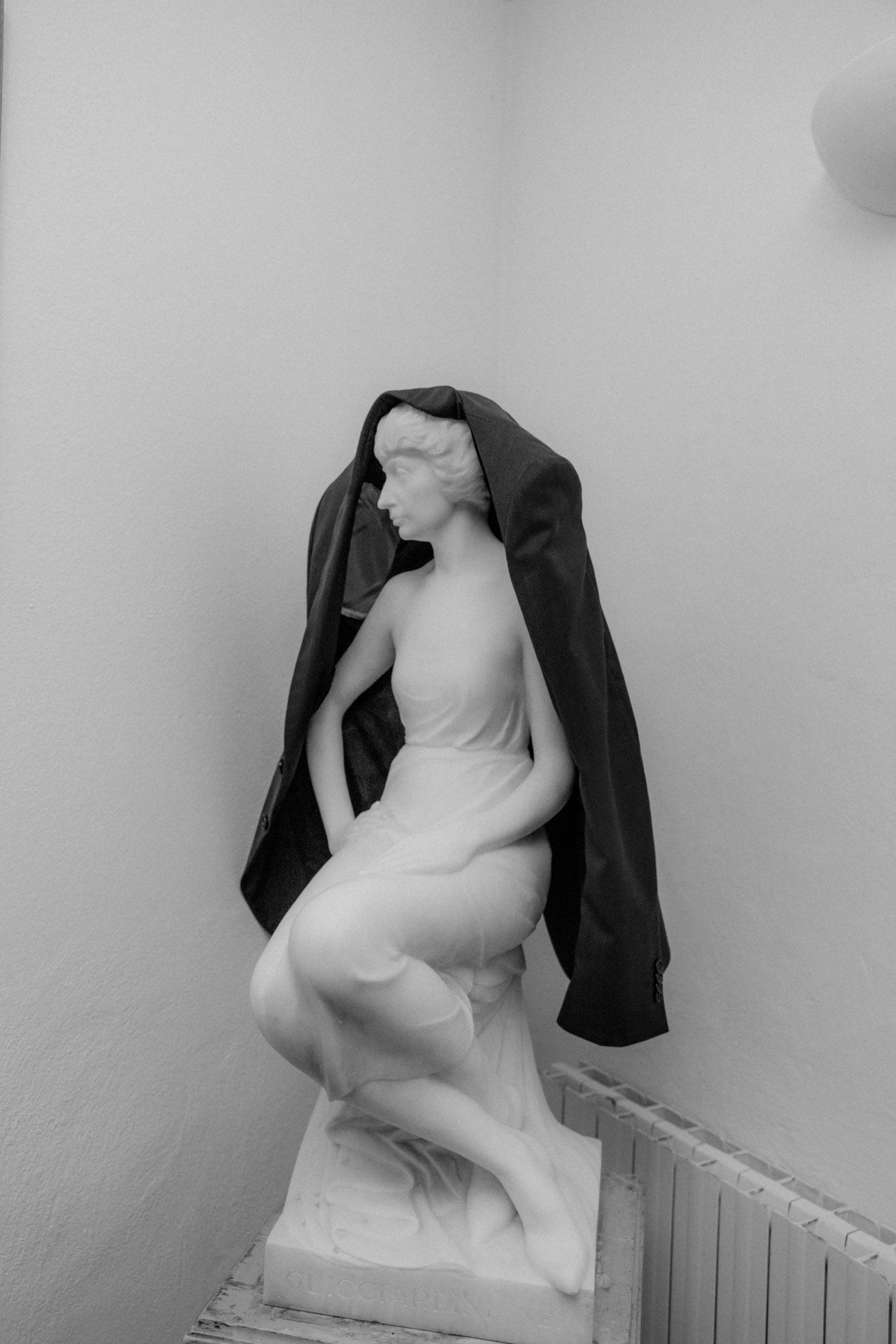 Black and white photo series showing a figure in dark clothing against a white wall in various dramatic poses.