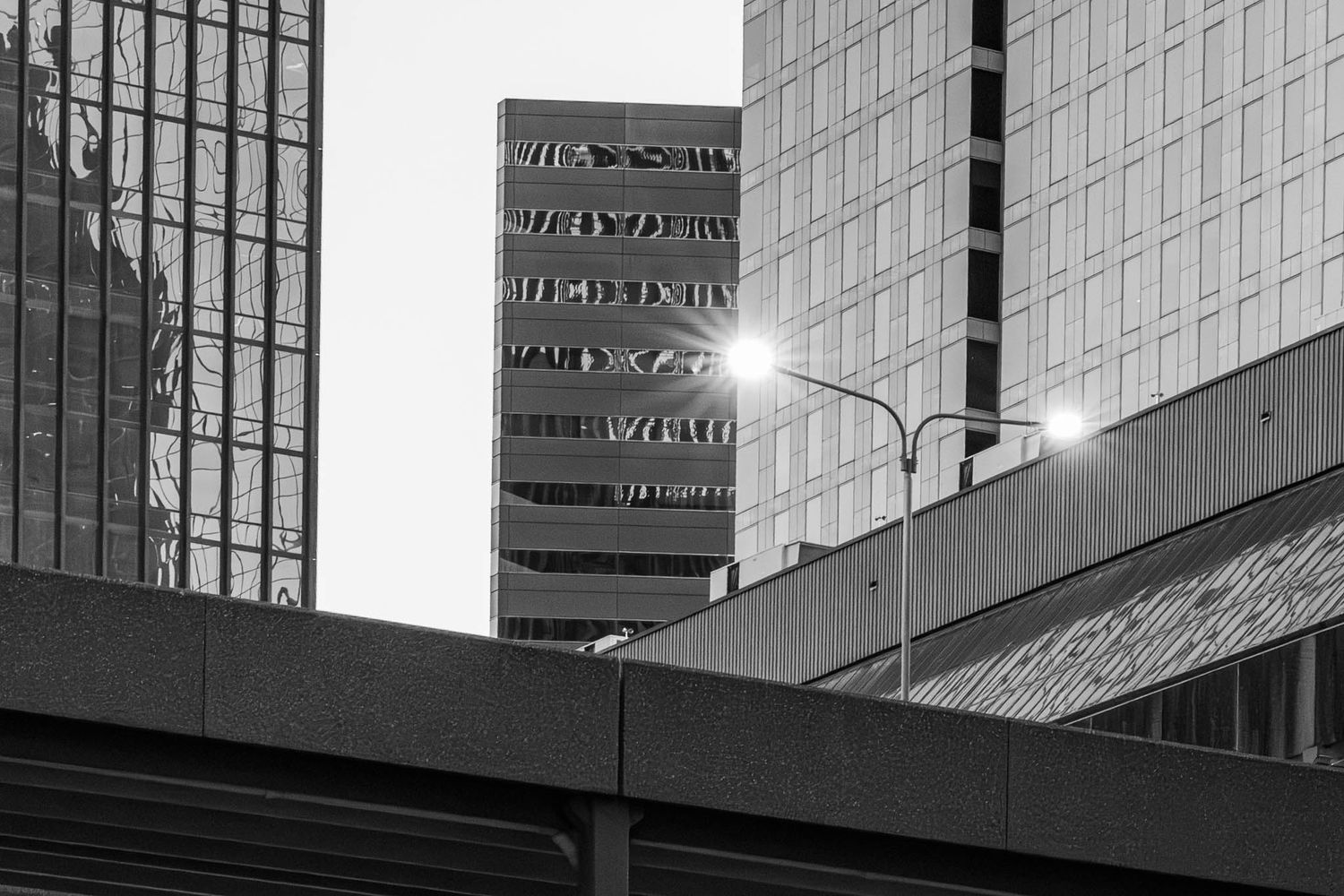 Architectural detail of a modern glass office building facade reflecting light and creating geometric patterns.